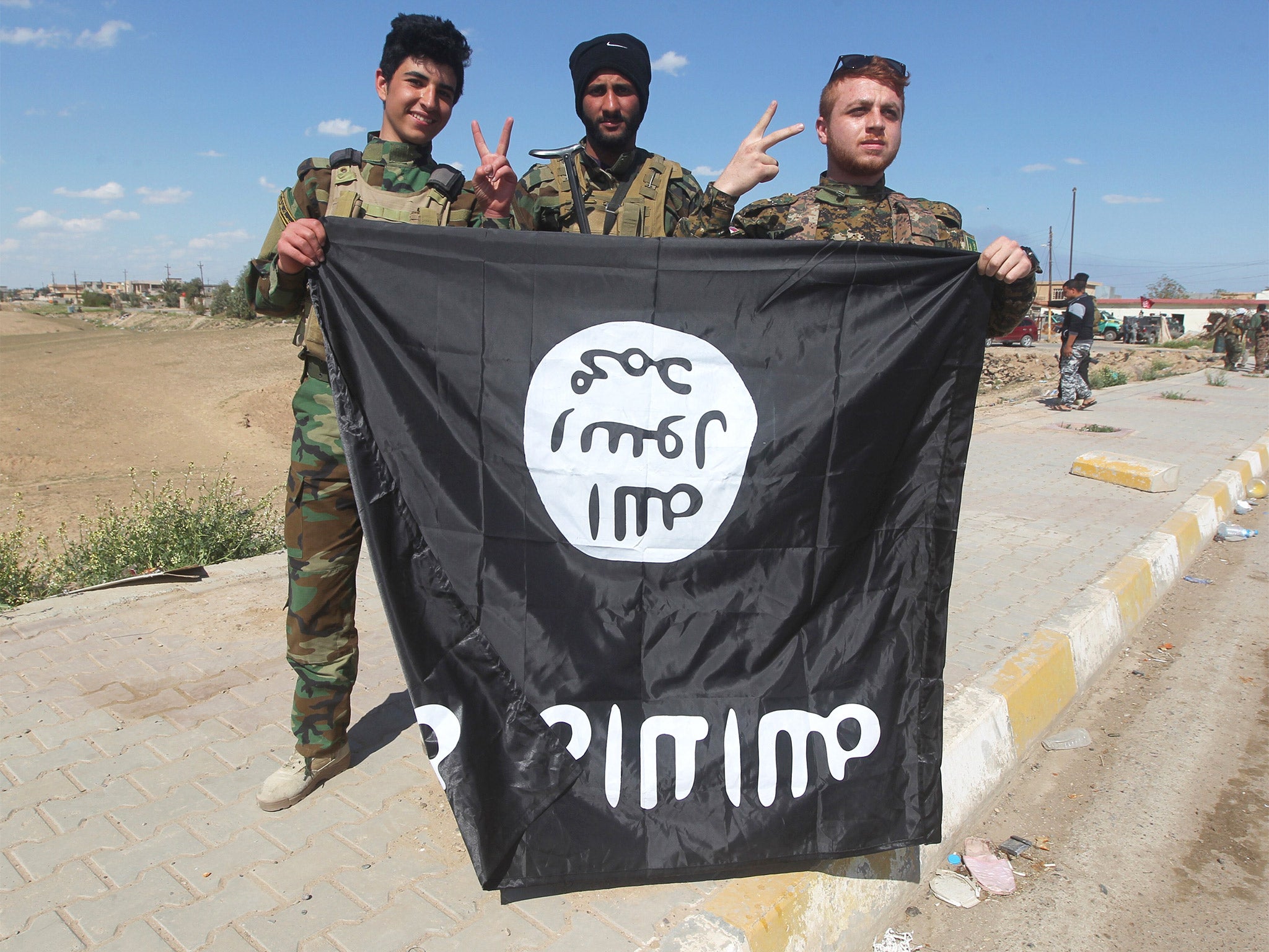 Iraqi Sunni and Shiite fighters pose with an Islamic State flag in Al-Alam, northeast of the Iraqi city of Tikrit, after recapturing the town earlier in the month (Getty)