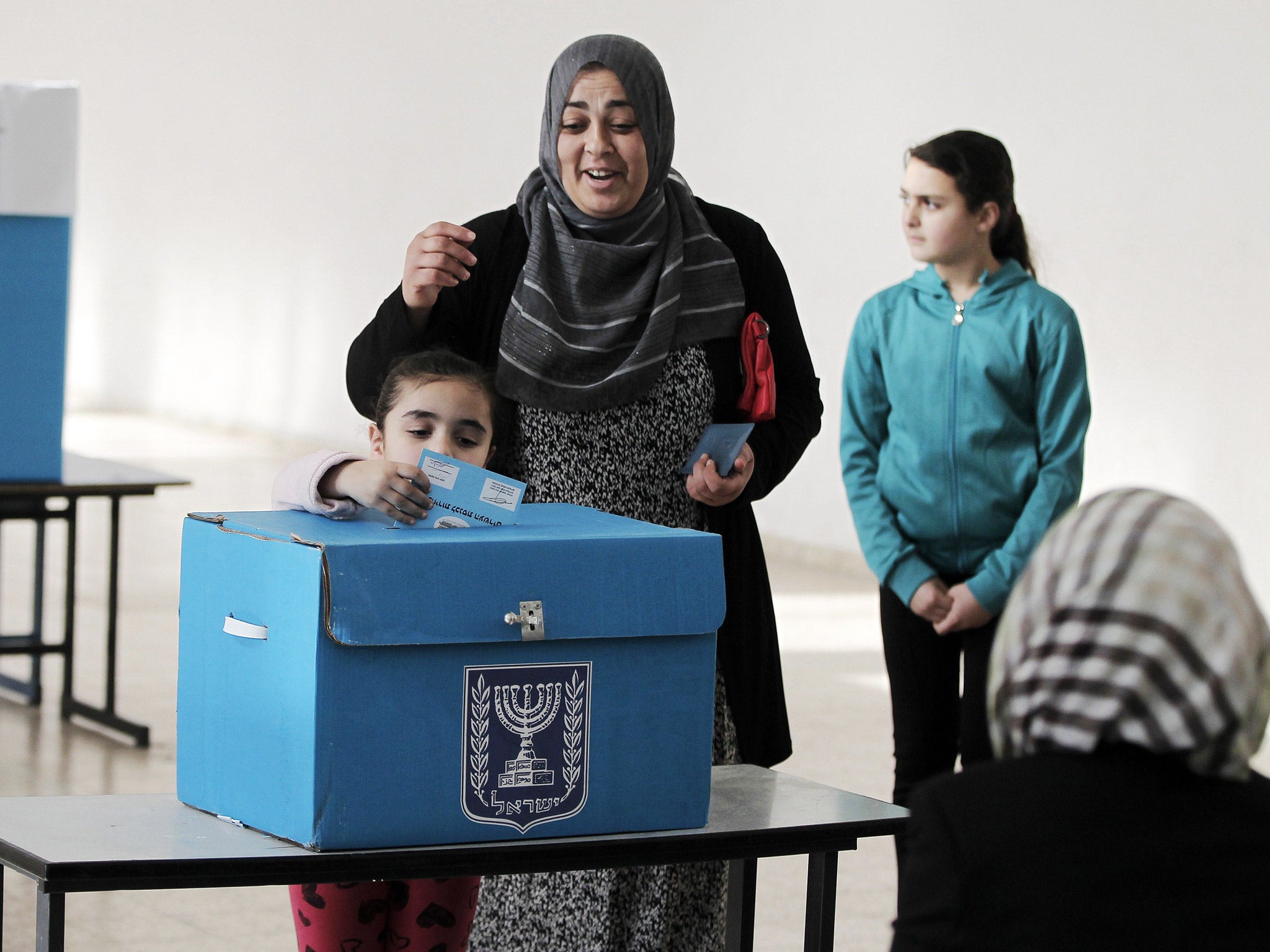 An Arab Israeli girl casts her mother's ballot at a polling station on Tuesday