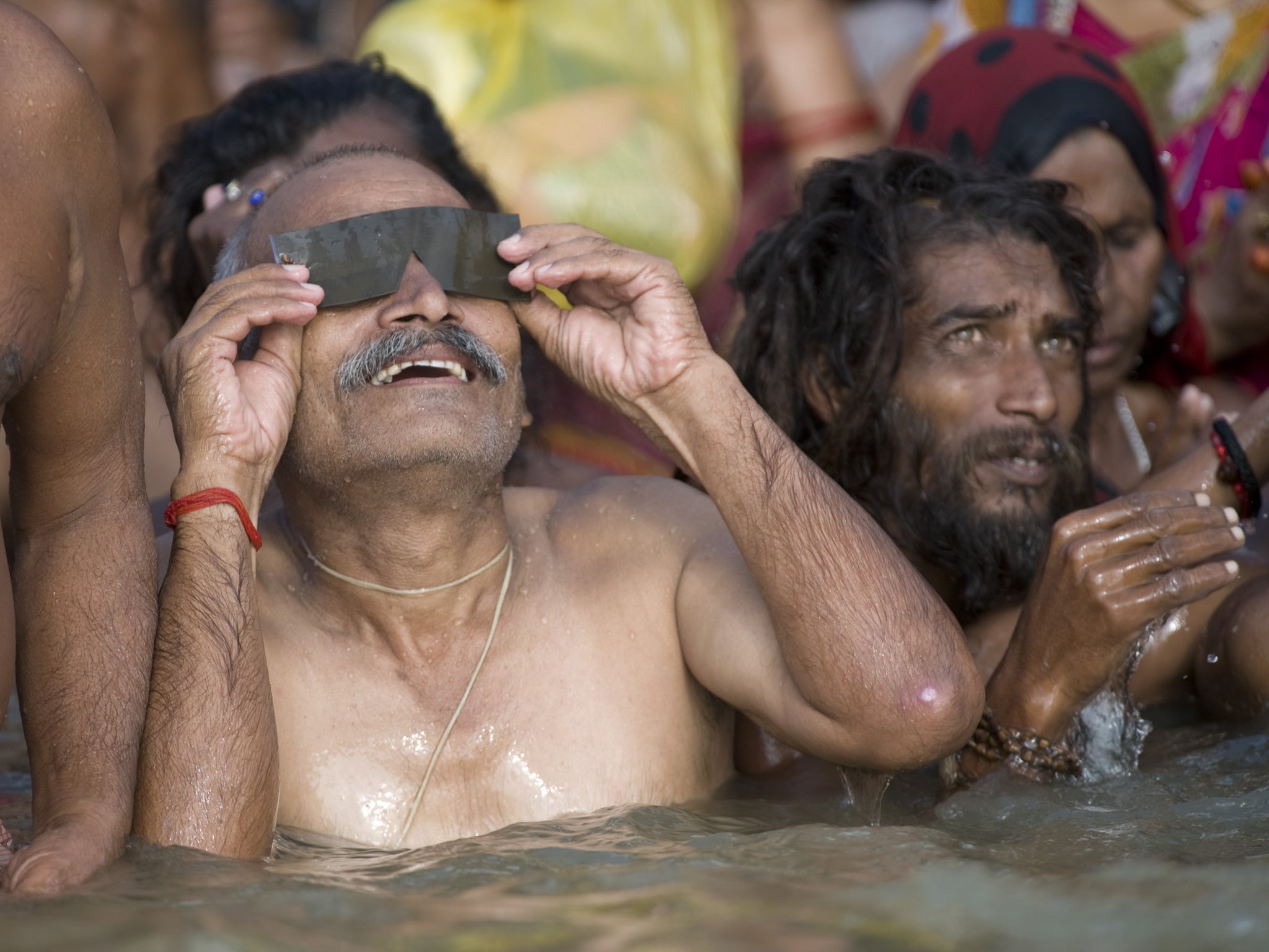 A Hindu man watches a solar eclipse as he takes a bath in the Ganges river in the Indian city of Varanasi on July 22, 2009. The longest solar eclipse of the 21st century cast a shadow over much of Asia, plunging hundreds of millions into darkness across t