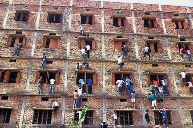 Los indios escalan la pared de un edificio para ayudar a los estudiantes que aparecen en un examen en Hajipur, en el estado de Bihar, en el este de la India, el 18 de marzo.