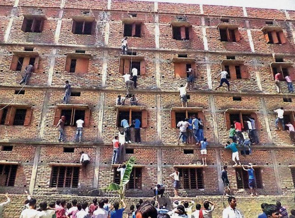 Indians climb the wall of a building to help students appearing in an examination in Hajipur, in the eastern Indian state of Bihar, on 18 March