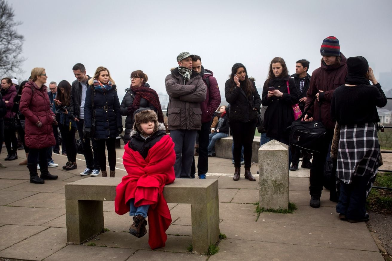 People gather outside the Royal Observatory in Greenwich hoping to see the eclipse