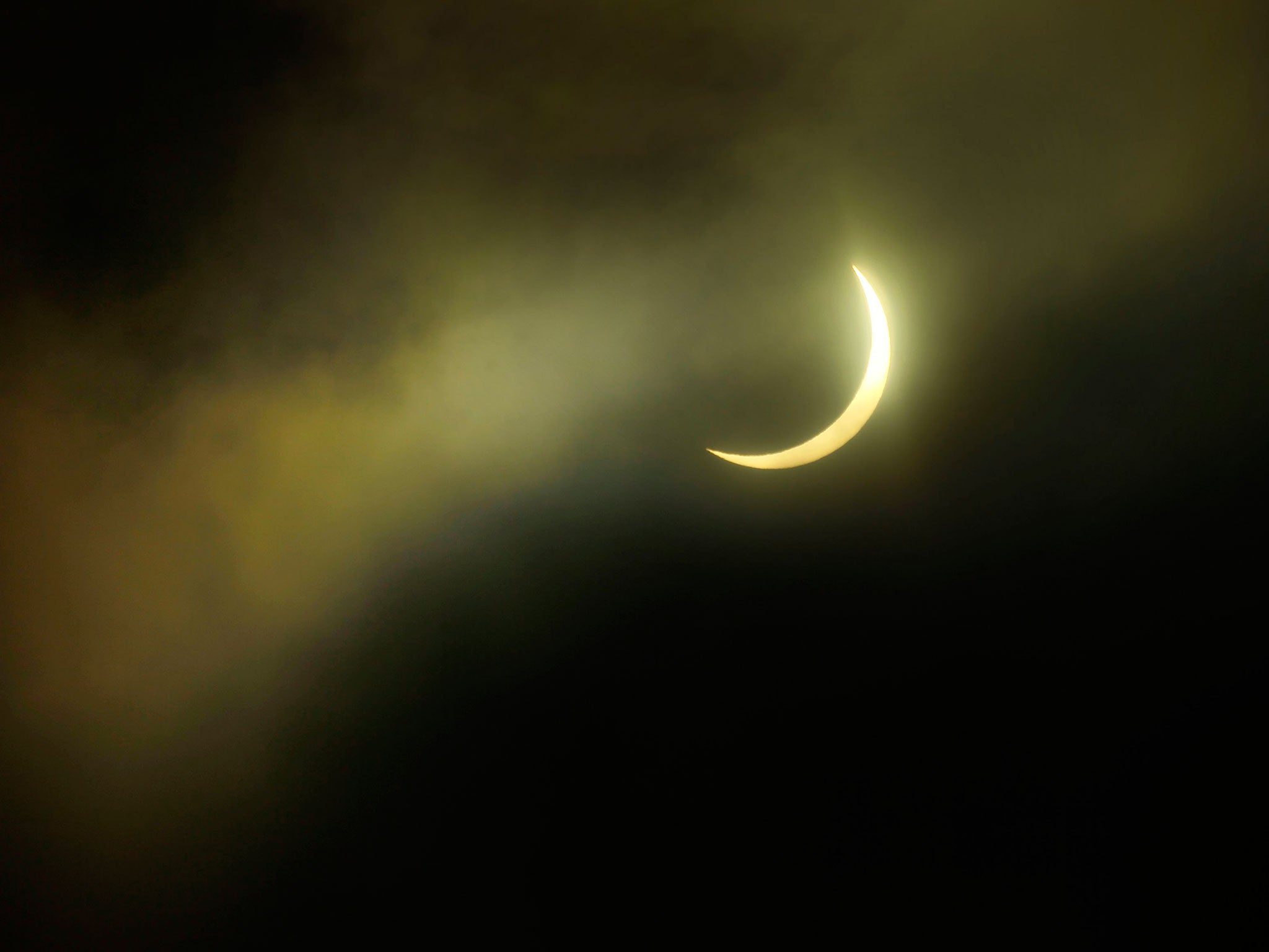 An eclipse of the sun passes behind a cloud, from Carlton Hill in Edinburgh