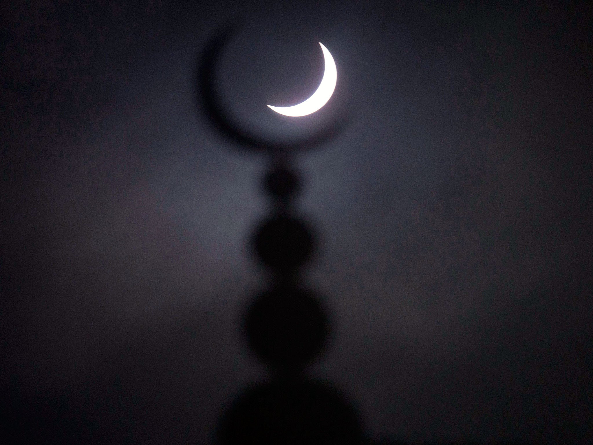 A partial solar eclipse in seen above a mosque in Oxford, central England