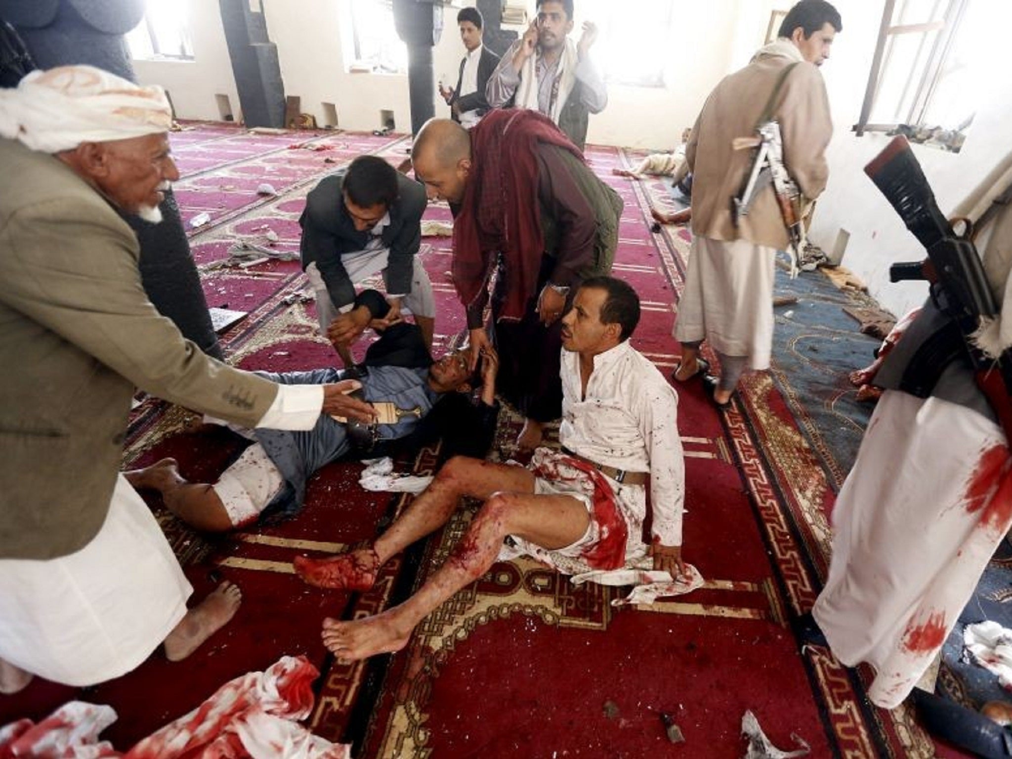 Men attend to injured worshippers at one of the targeted mosques in Sanaa, Yemen