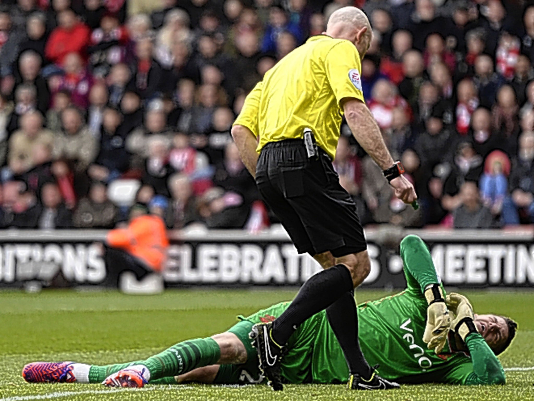 Referee Roger East looks over stricken Southampton goalkeeper Fraser Forster after he injured his knee against Burnley