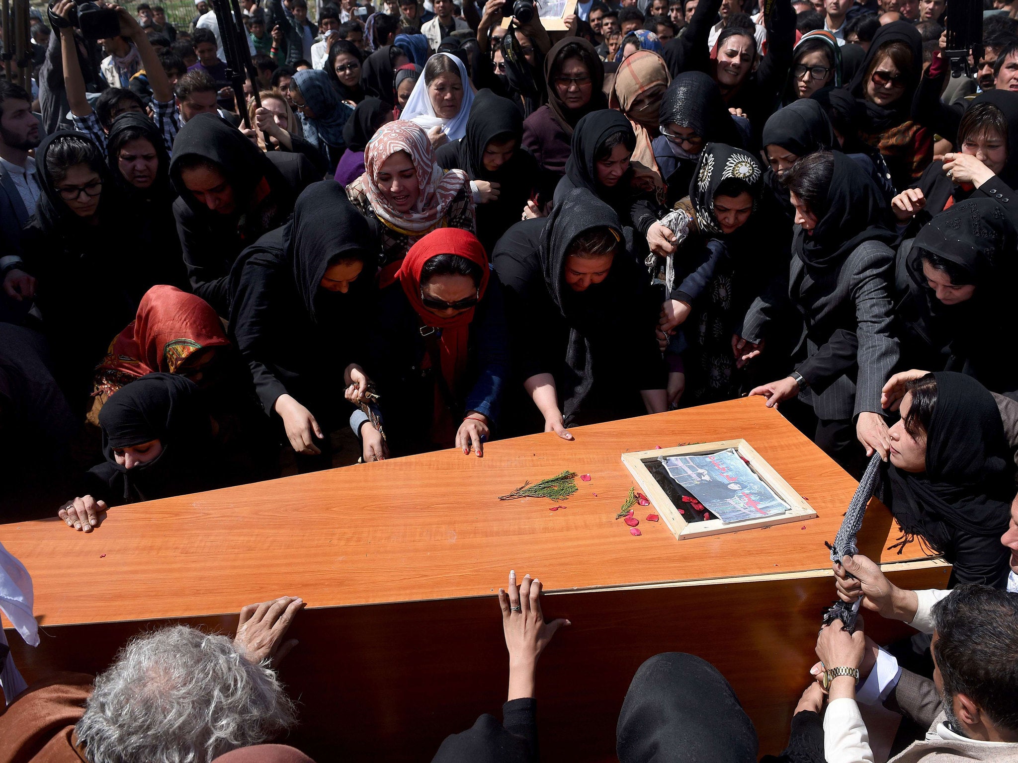 Activist women and Afghan men lower the coffin of Farkhunda at the cemetary in central Kabul