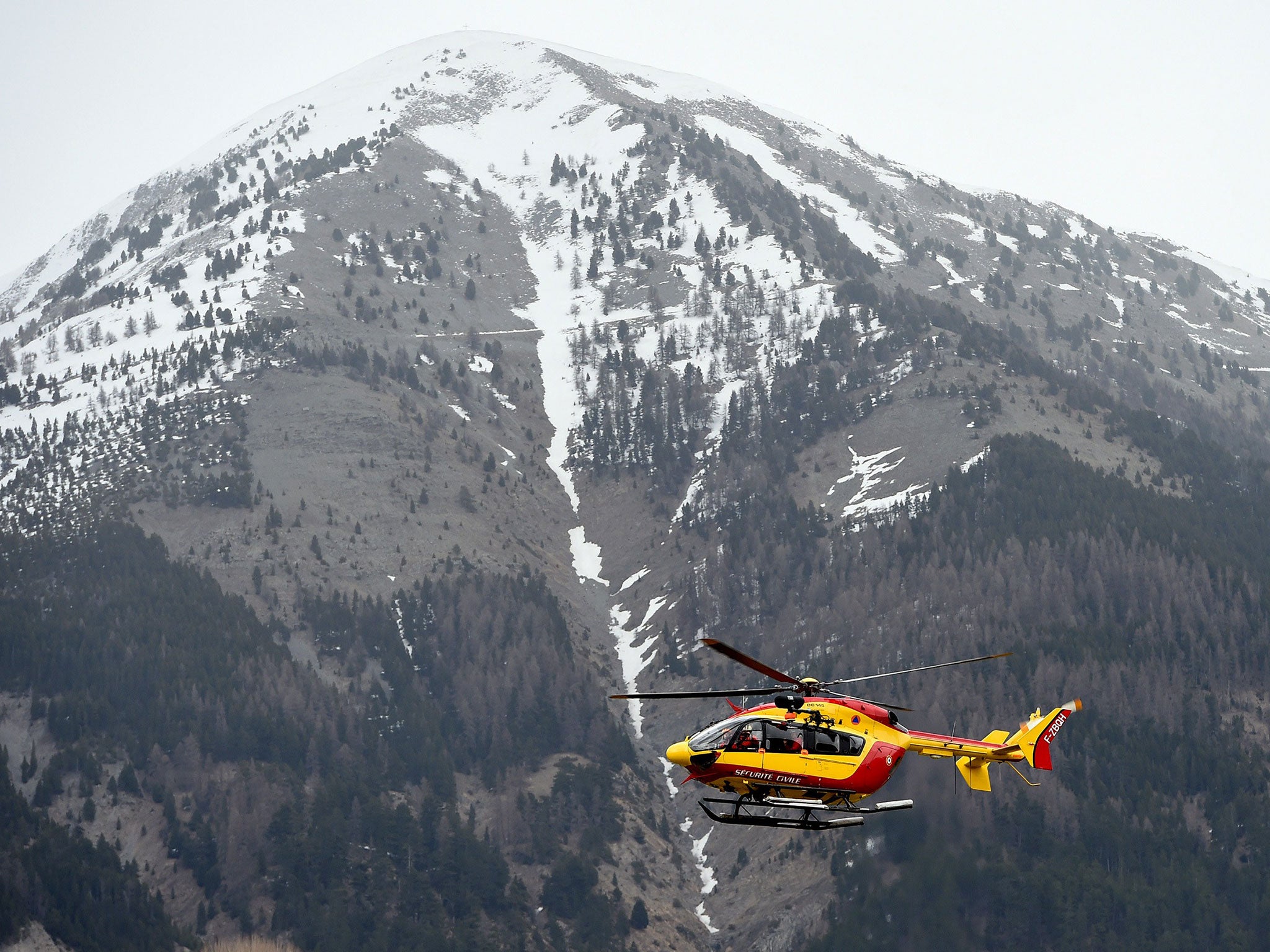 An helicopter of civil security services flies over the site where a Germanwings Airbus A320 crashed in the French Alps