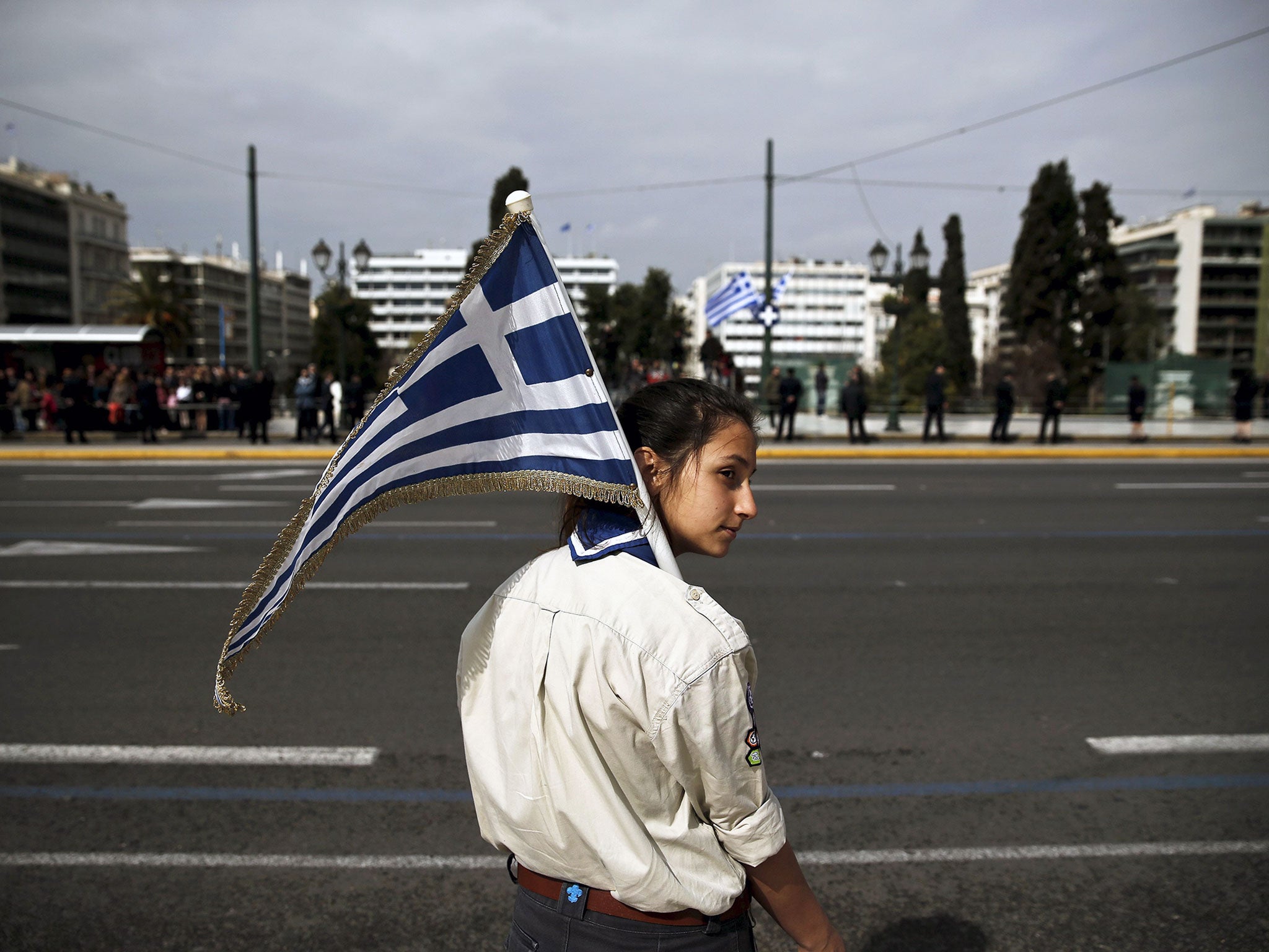 A girl scout holds a Greek national flag ahead of a student parade in Athens, a day before a military parade to mark Greece's Independence Day