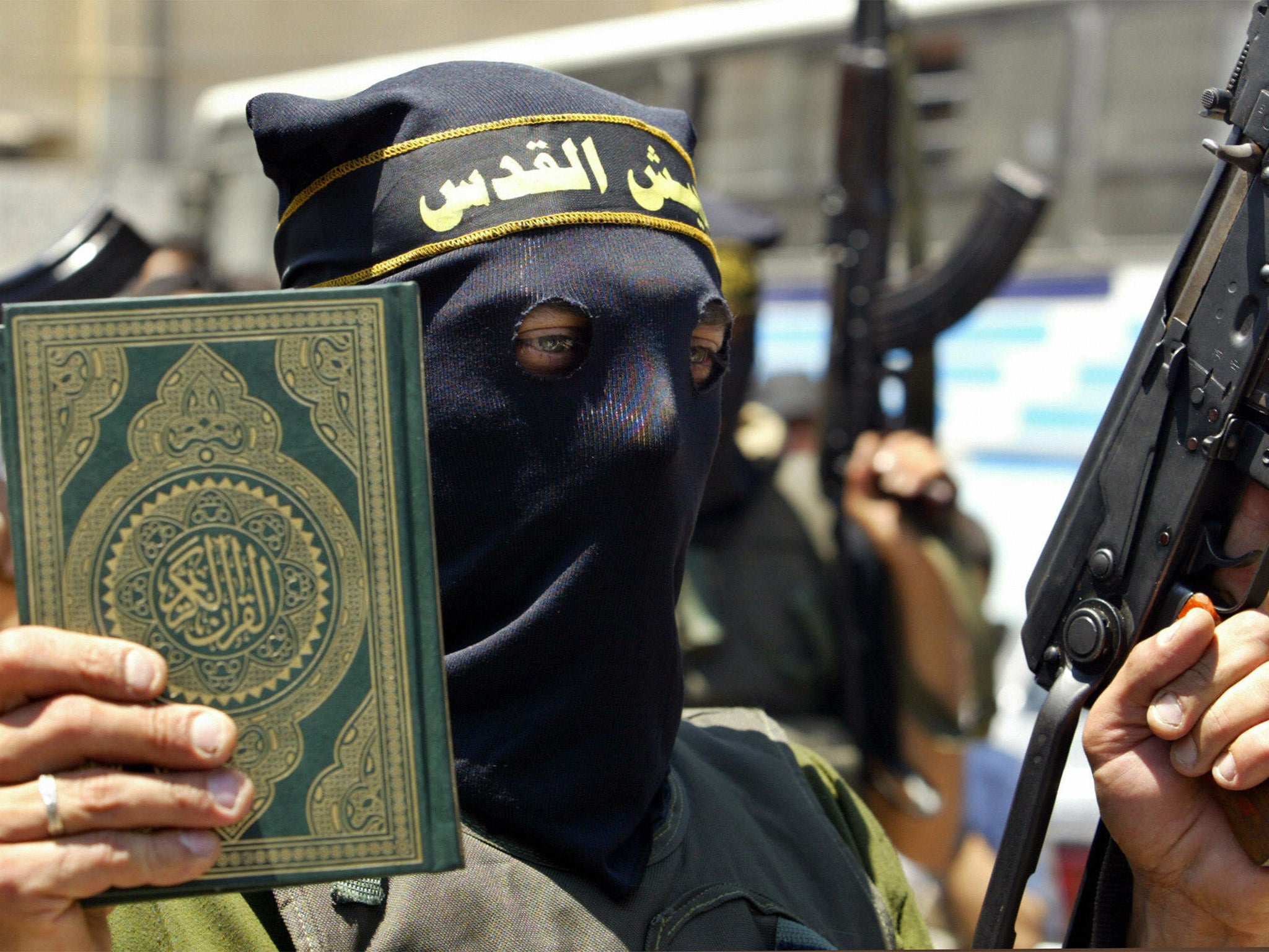 An Islamic Jihad militant holds up a copy of the Koran in one hand and an automatic rifle in the other during a rally in Beit Lahia in the northern Gaza Strip (Getty)