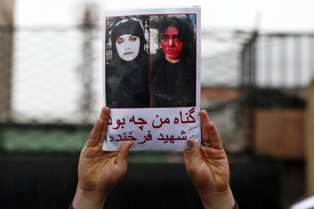 An Afghan demonstrator holds a placard reading in Dari 'What was my sin?' with a picture of Farkhanda