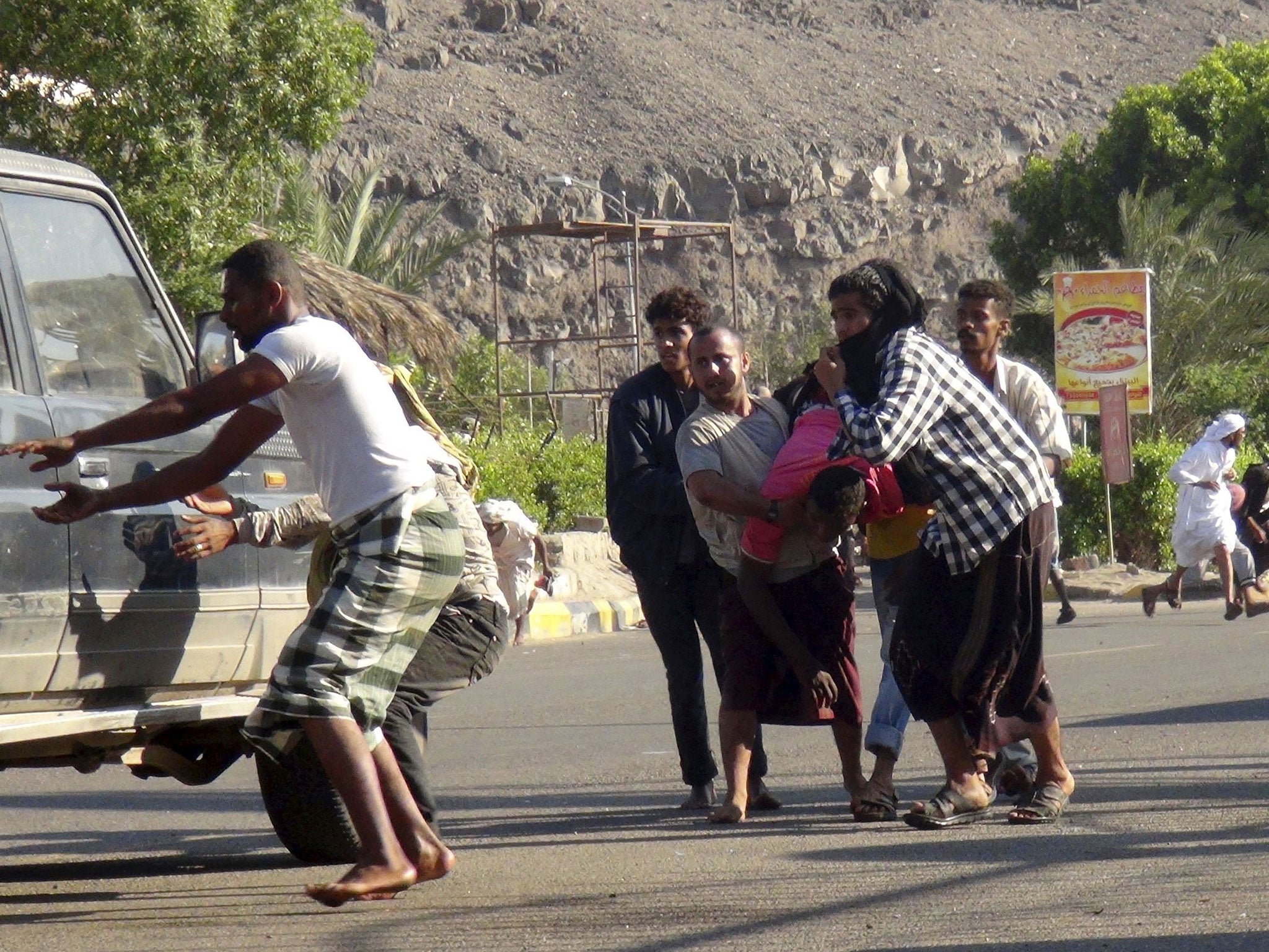 People carry a man injured during a gunfire at an army base in Yemen's southern port city of Aden