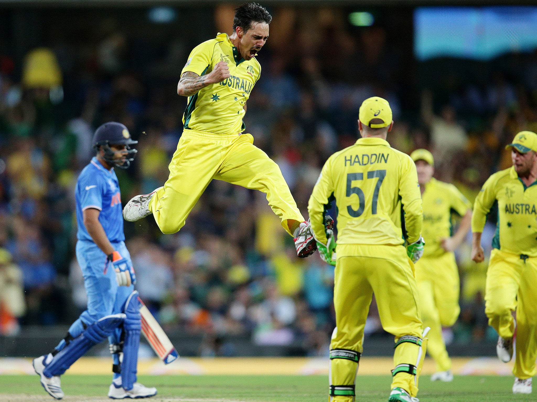 Australia's Mitchell Johnson leaps in the air as he celebrates after taking the wicket of India's Rohit Sharma, left, during their Cricket World Cup semifinal in Sydney, Australia