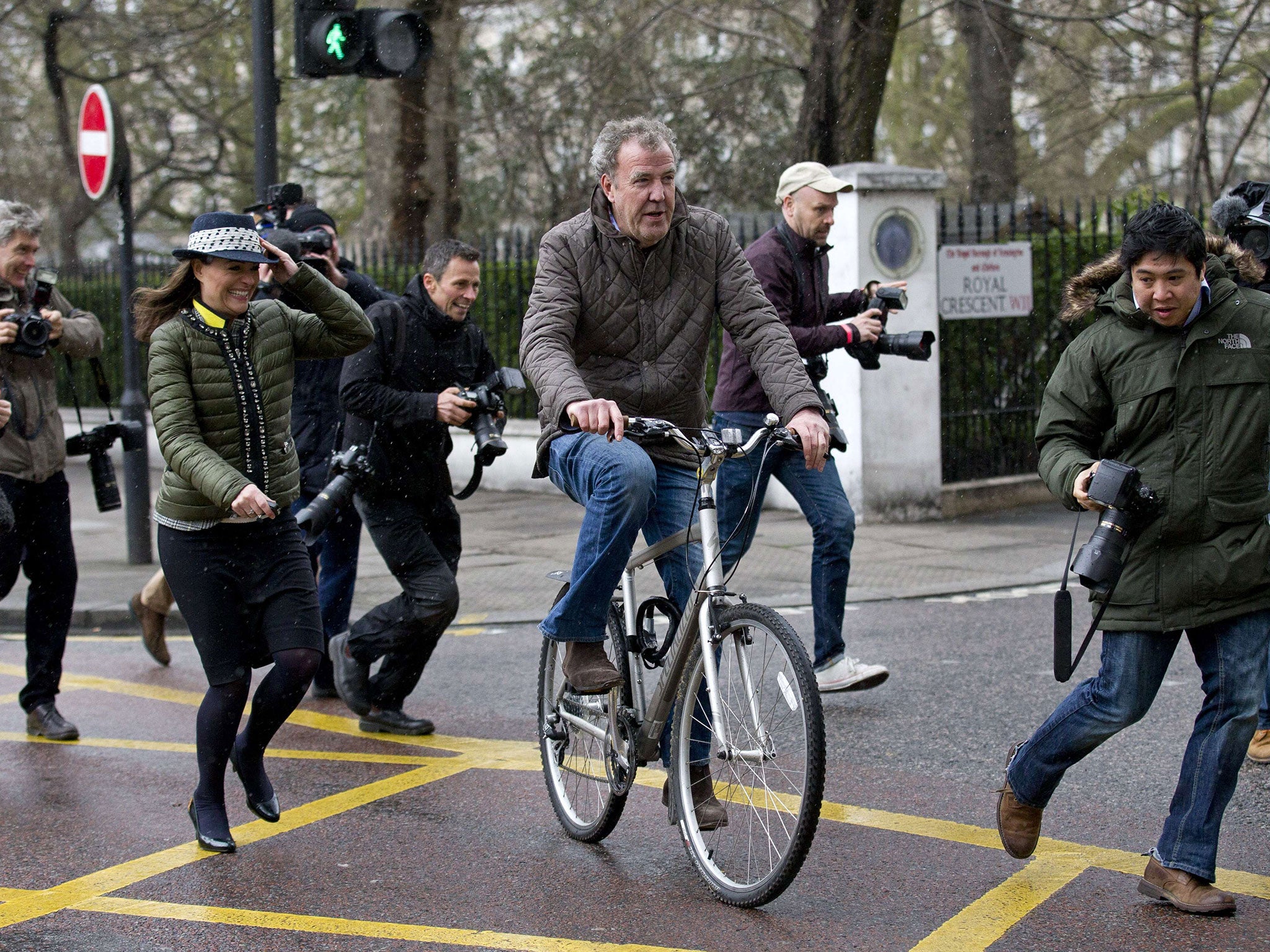 Jeremy Clarkson is surrounded by media personnel as he leaves his home on a bicycle in London