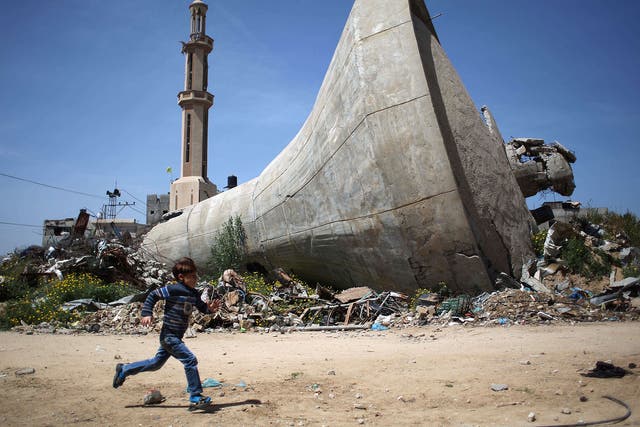 A Palestinian child runs past a water tank that was destroyed in Israeli bombing during the 50-day war between Israel and Hamas militants in the summer of 2014, in the village of Khuzaa, east of Khan Yunis, in the southern Gaza Strip
