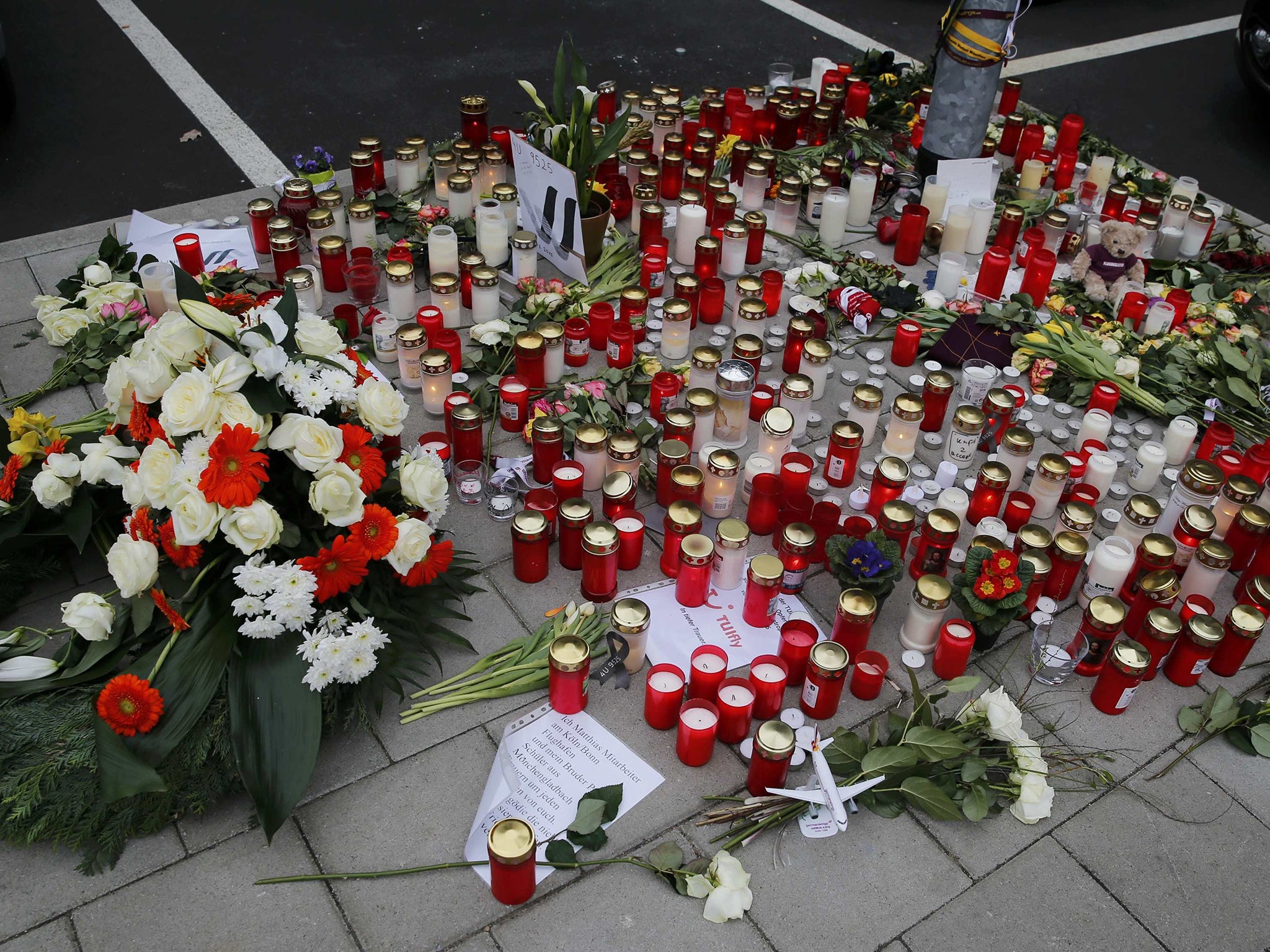 Flowers and lit candles are placed on the ground in Cologne Bonn airport