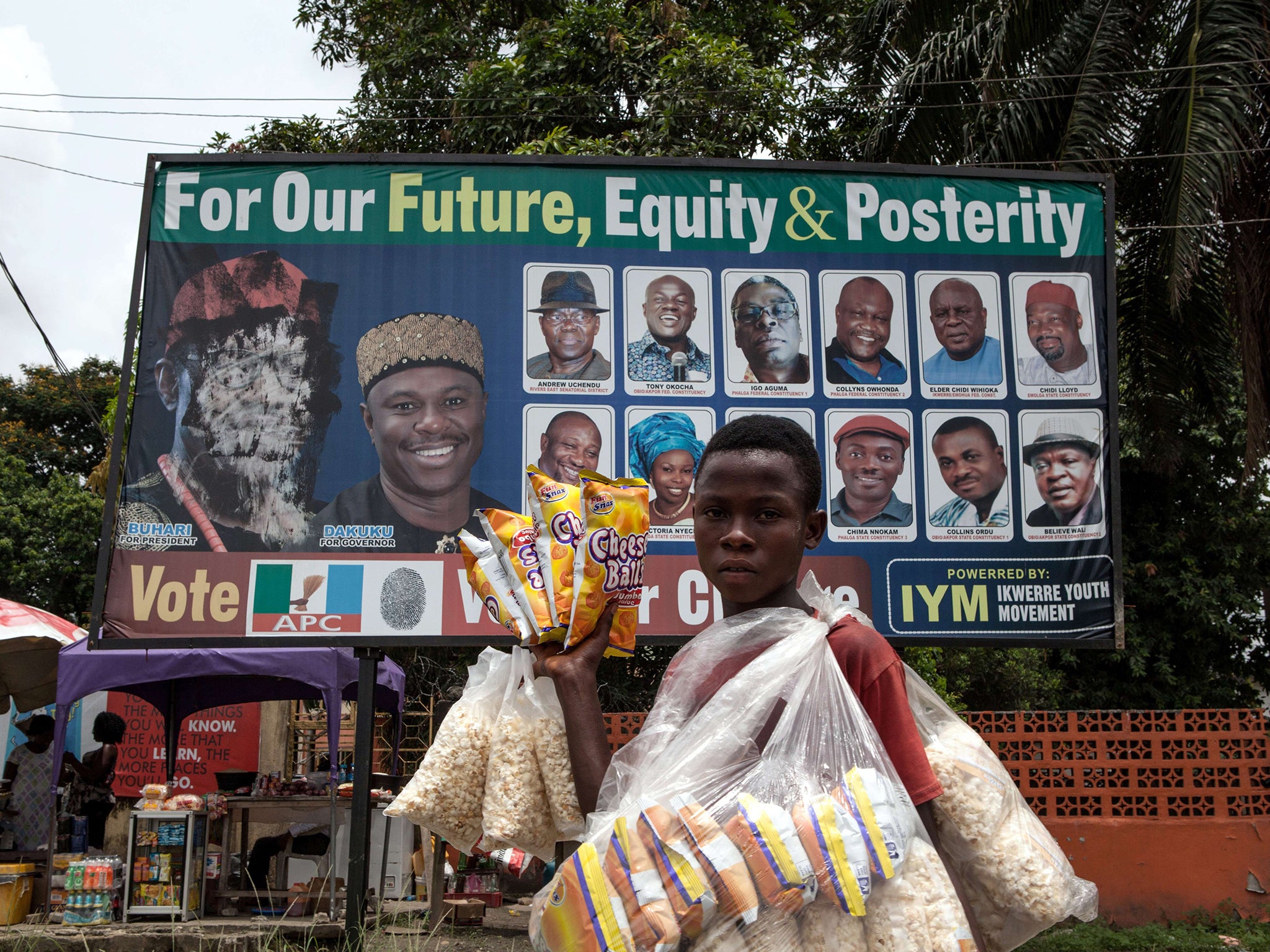 A vendor sells popcorn in front of a defaced election poster of the former military ruler Muhammadu Buhari in the oil hub of Port Harcourt yesterday. Presidential elections take place tomorrow