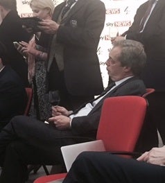 Nigel Farage sips red wine as he watches from the spin room