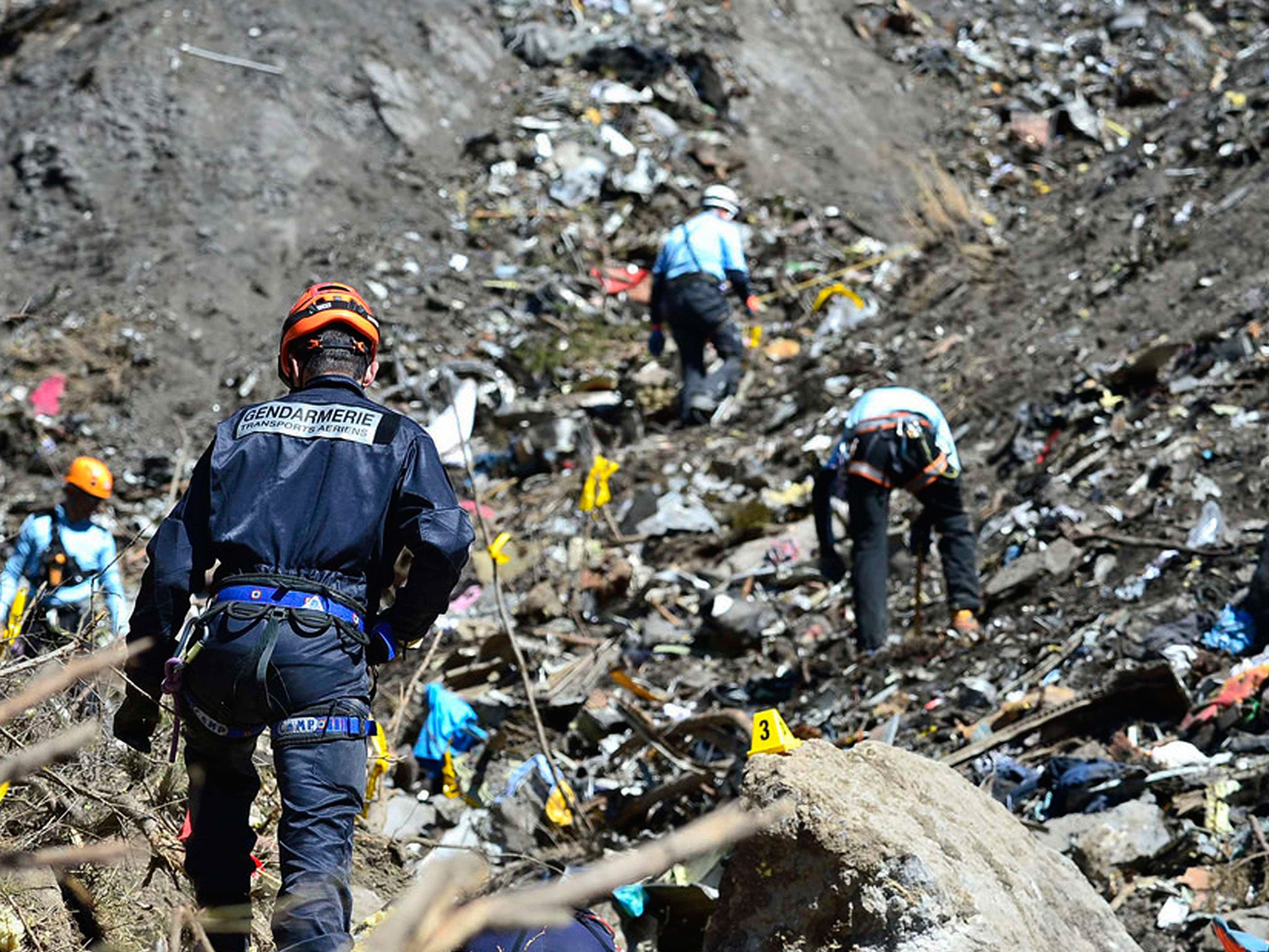 French gendarmes and investigators make their way through debris from wreckage on the mountainside at the crash site of an Airbus A320, near Seyne-les-Alpes