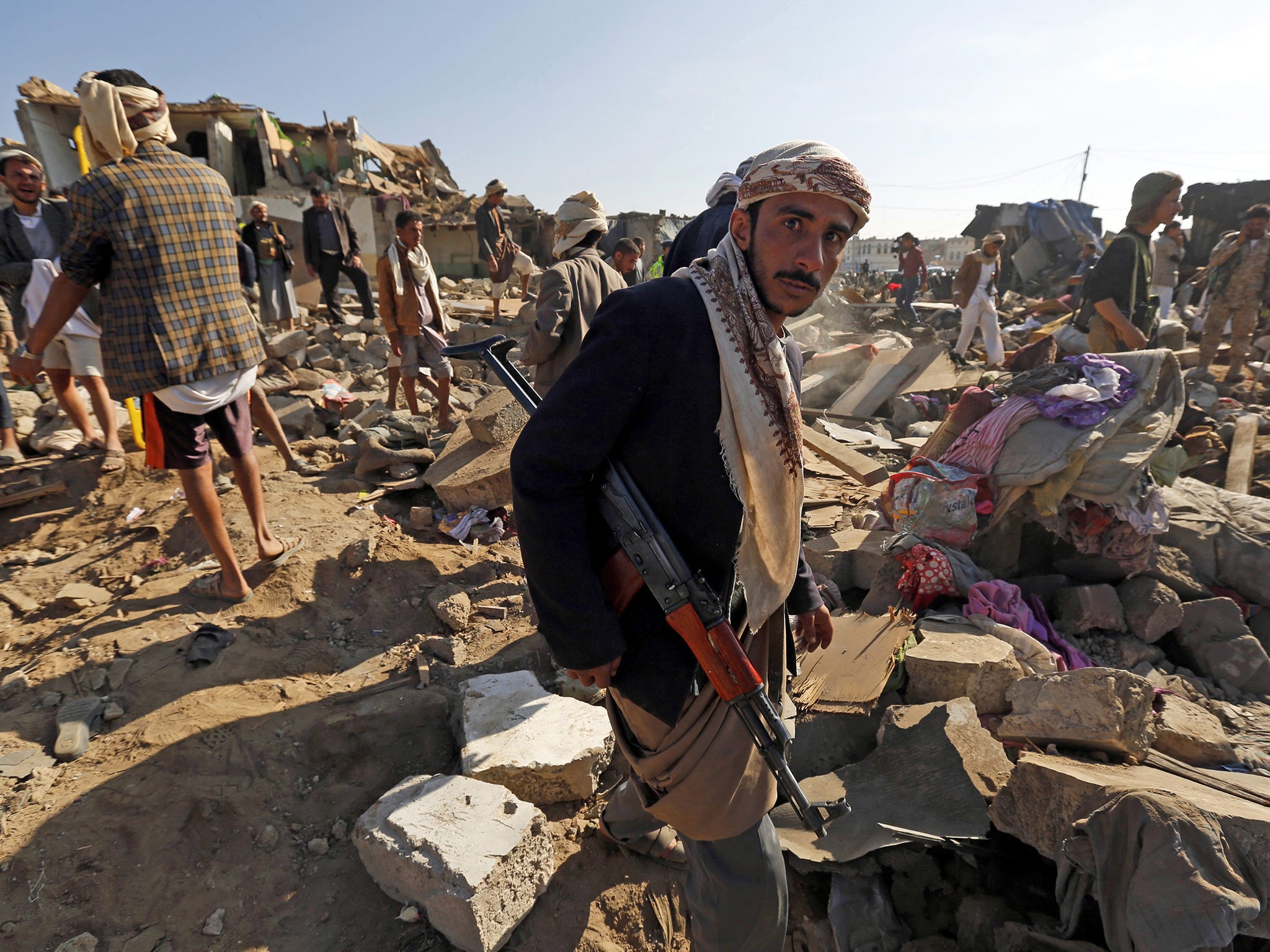 An armed member of the Houthi militia stands in the rubble of houses which were allegedly destroyed by a Saudi air strike