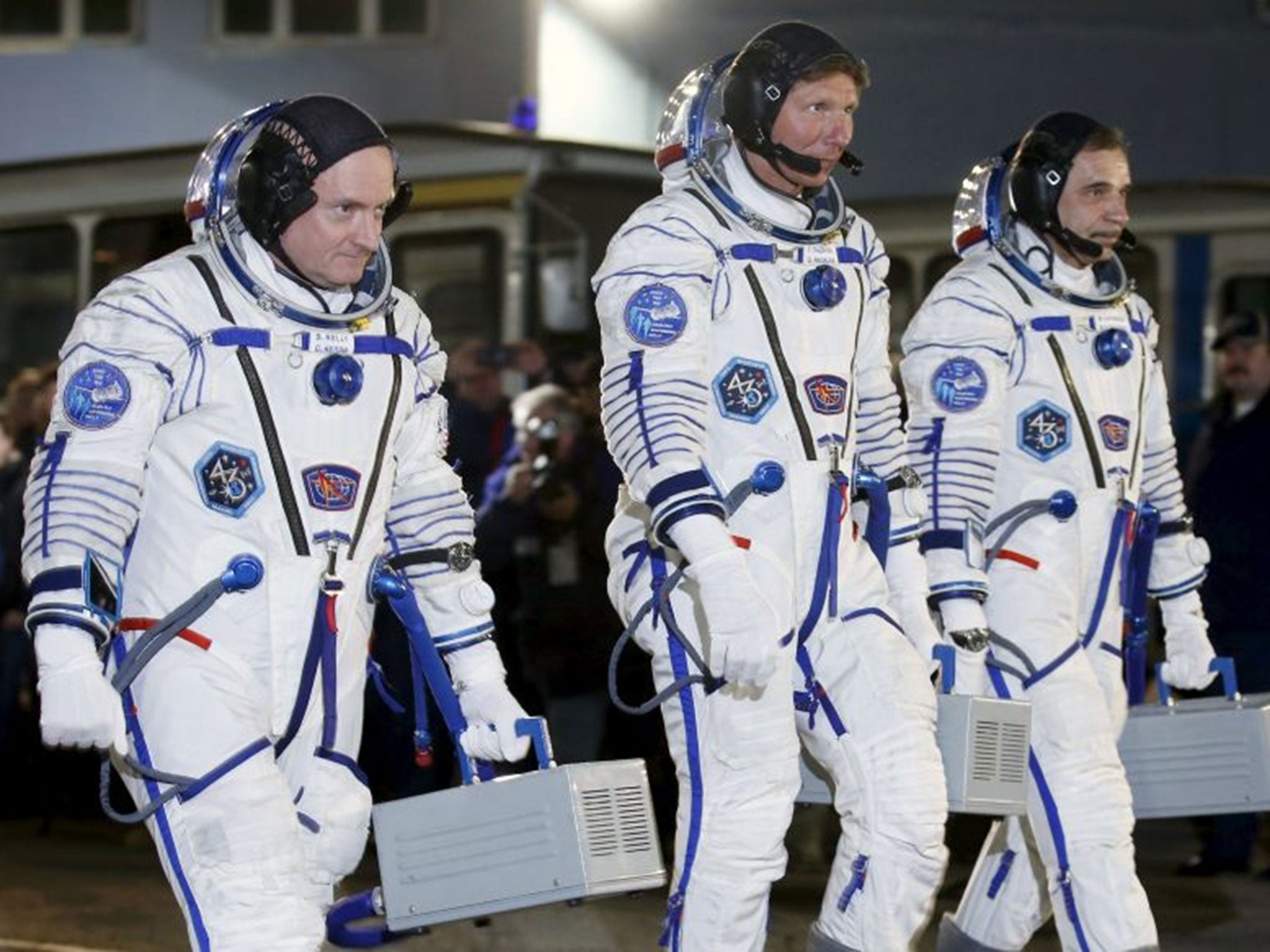 International Space Station (ISS) crew of (L-R) Scott Kelly of the U.S. and Mikhail Kornienko and Gennady Padalka of Russia walk after donning space suits at the Baikonur cosmodrome.