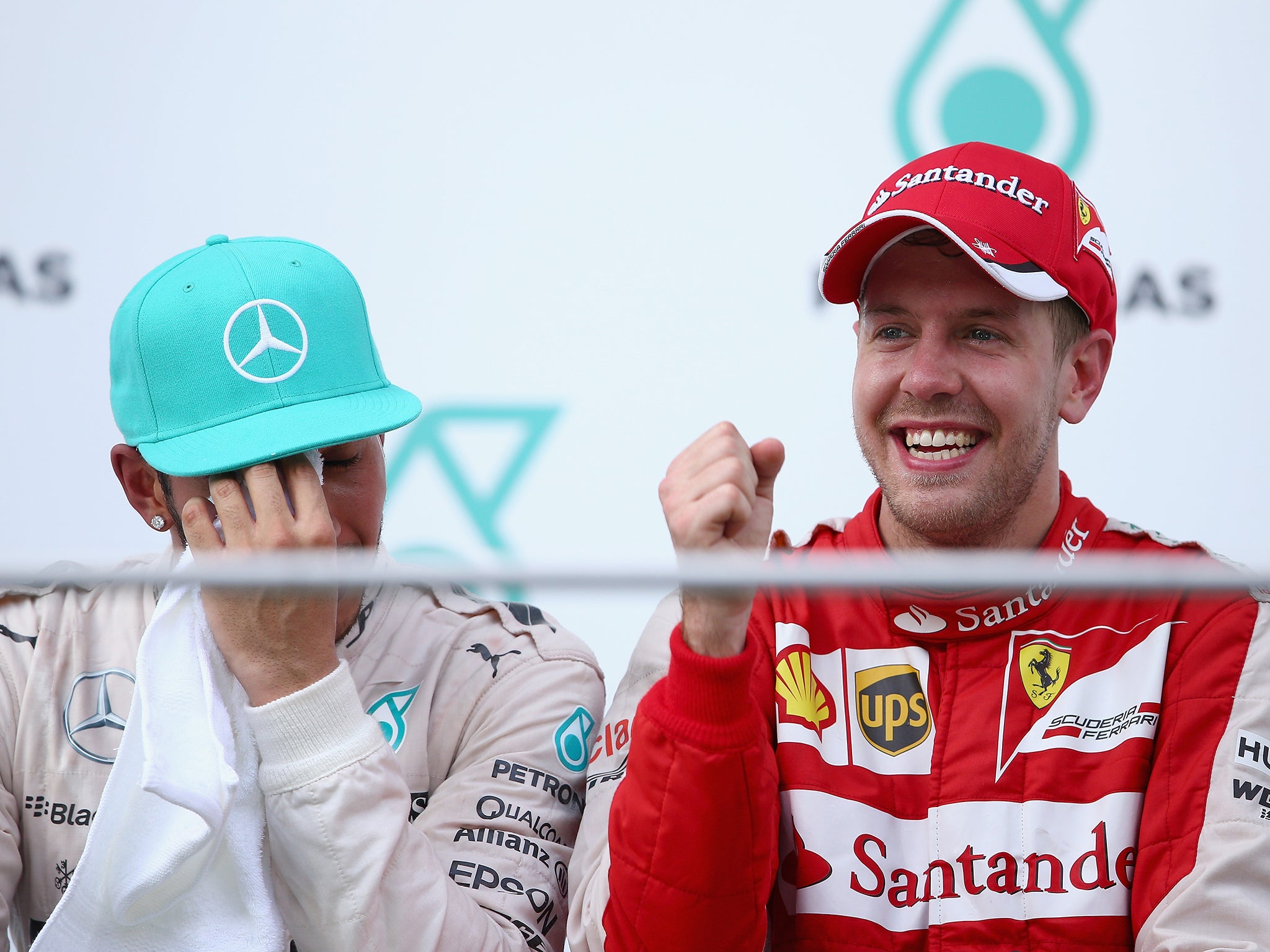 Sebastian Vettel of Germany and Ferrari celebrates on the podium next to Lewis Hamilton of Great Britain and Mercedes GP after winning the Malaysia Formula One Grand Prix at Sepang Circuit
