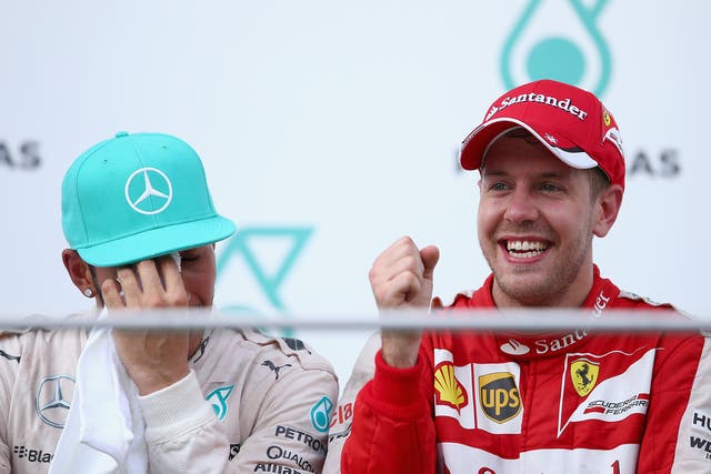 Sebastian Vettel of Germany and Ferrari celebrates on the podium next to Lewis Hamilton of Great Britain and Mercedes GP after winning the Malaysia Formula One Grand Prix at Sepang Circuit 