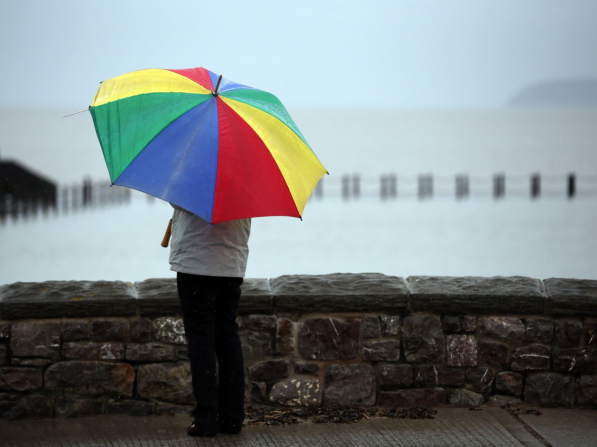 A woman shelters under a umbrella as the rain falls on the seafront on May 14, 2013 in Weston-Super-Mare, England.