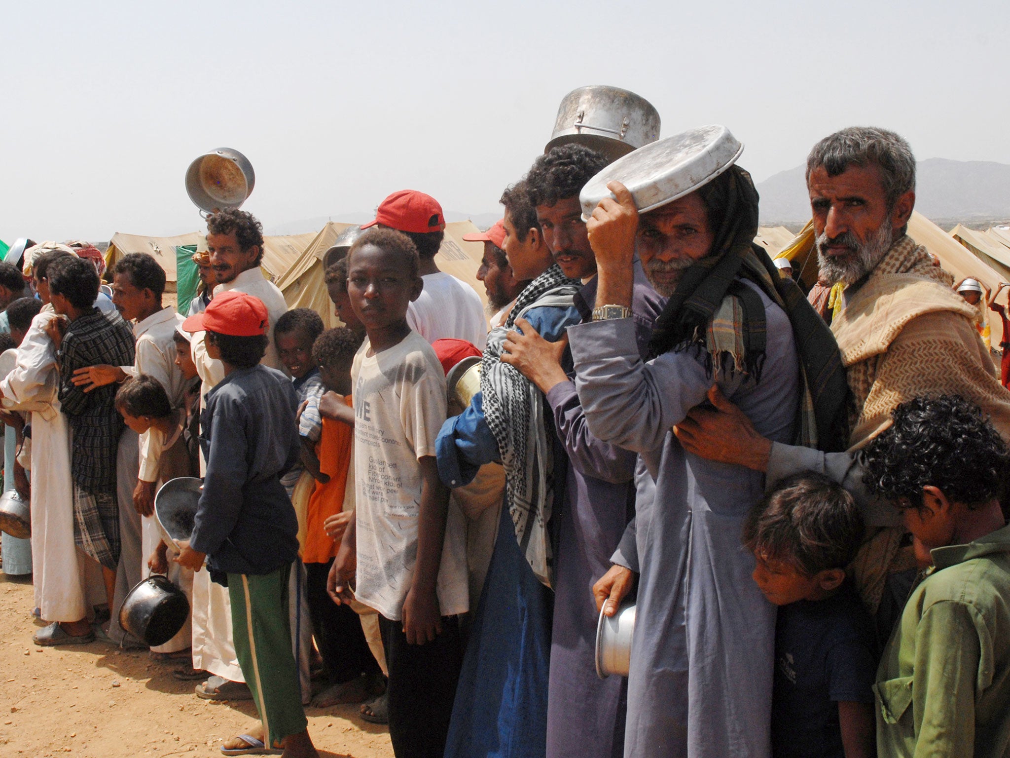 Yemeni refugees queue to get food aid at the Marzaq internally displaced people's camp in Harad in the northwestern province of Hajjah  