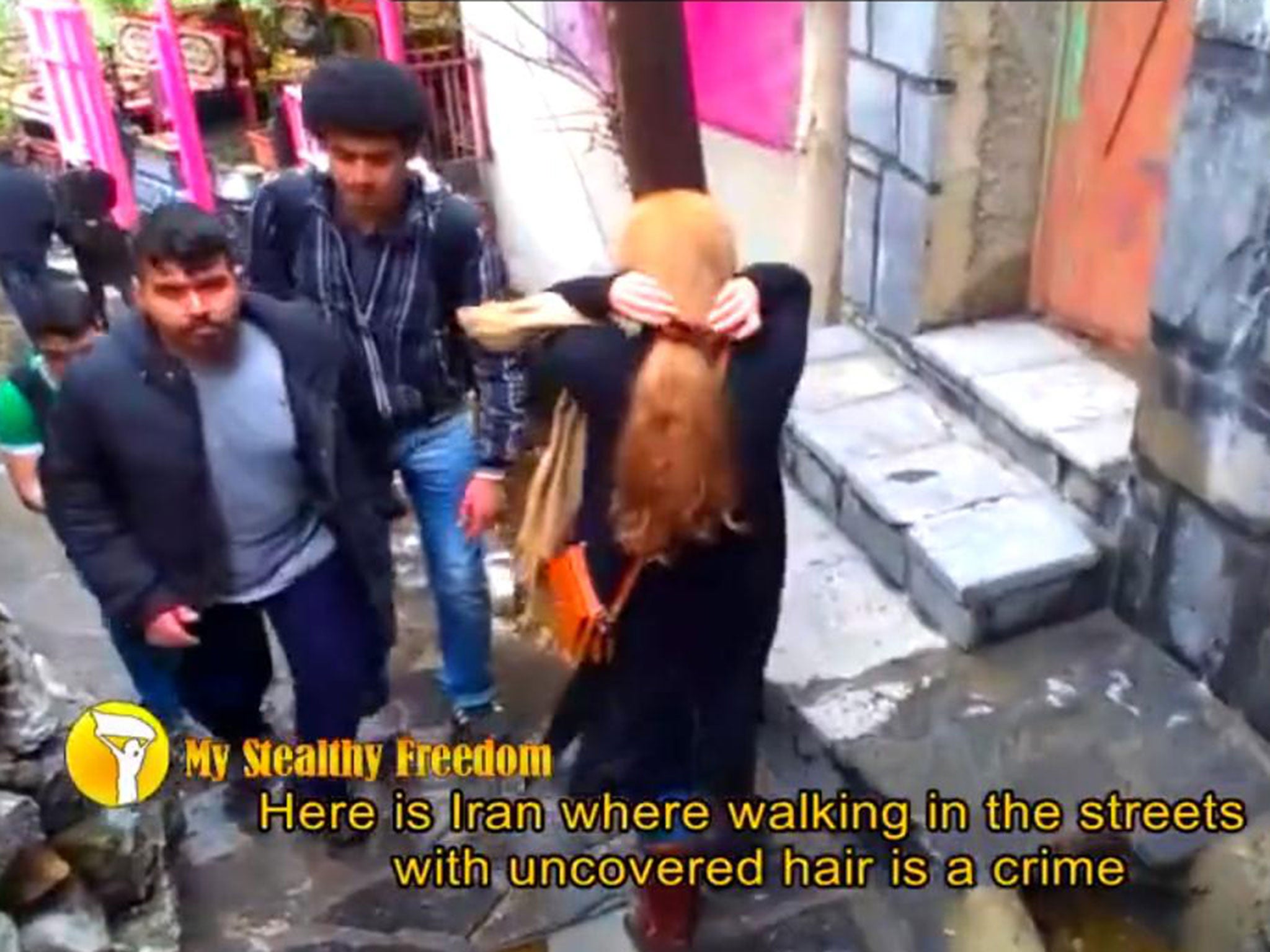 A woman walks through Tehran with her head uncovered 