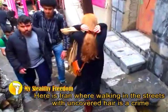 A woman walks through Tehran with her head uncovered 