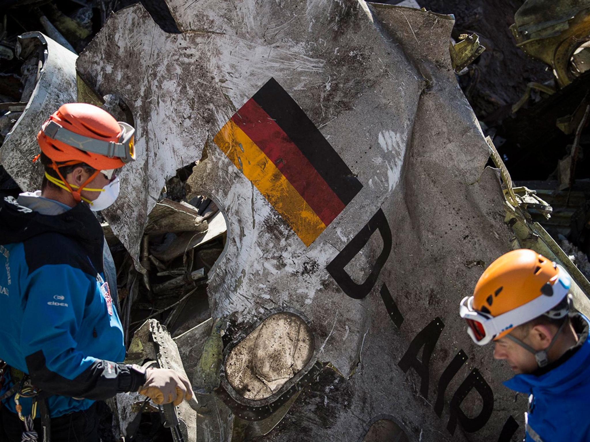 French gendarmes work near debris from the wreckage showing a German flag at the crash site of an Airbus A320, near Seyne-les-Alpes