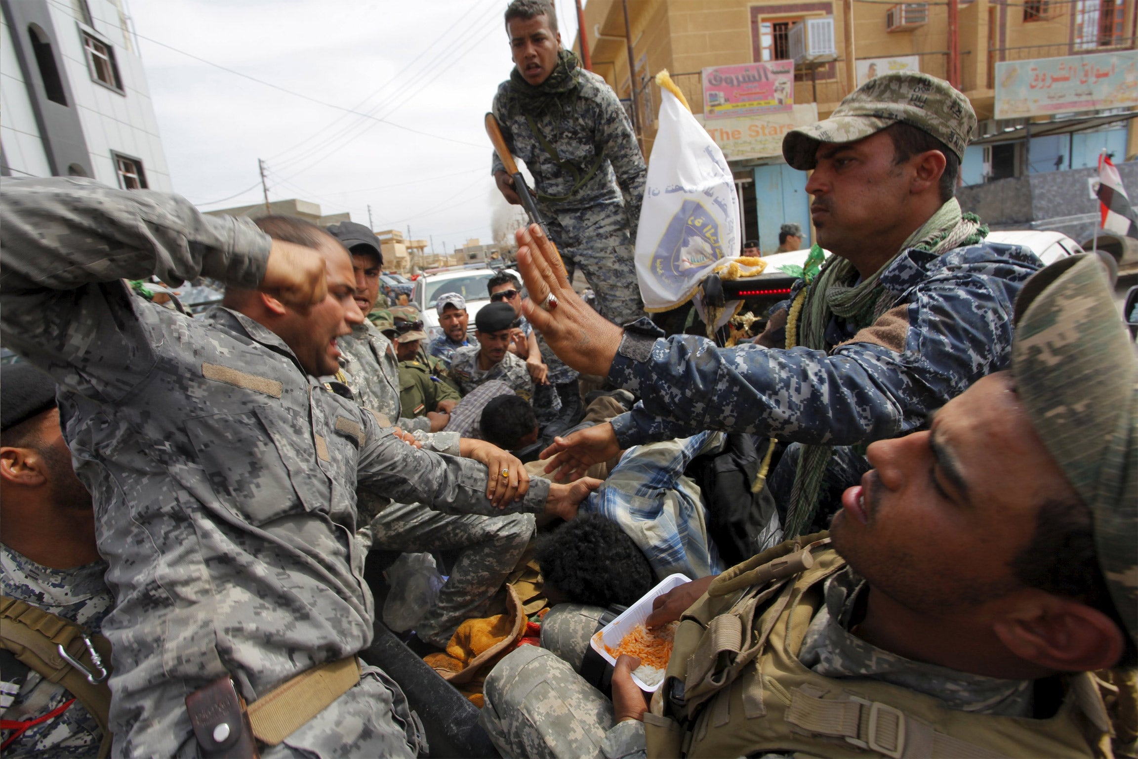 A member from the Iraqi security forces beats an Isis insurgent, who was captured in Tikrit
