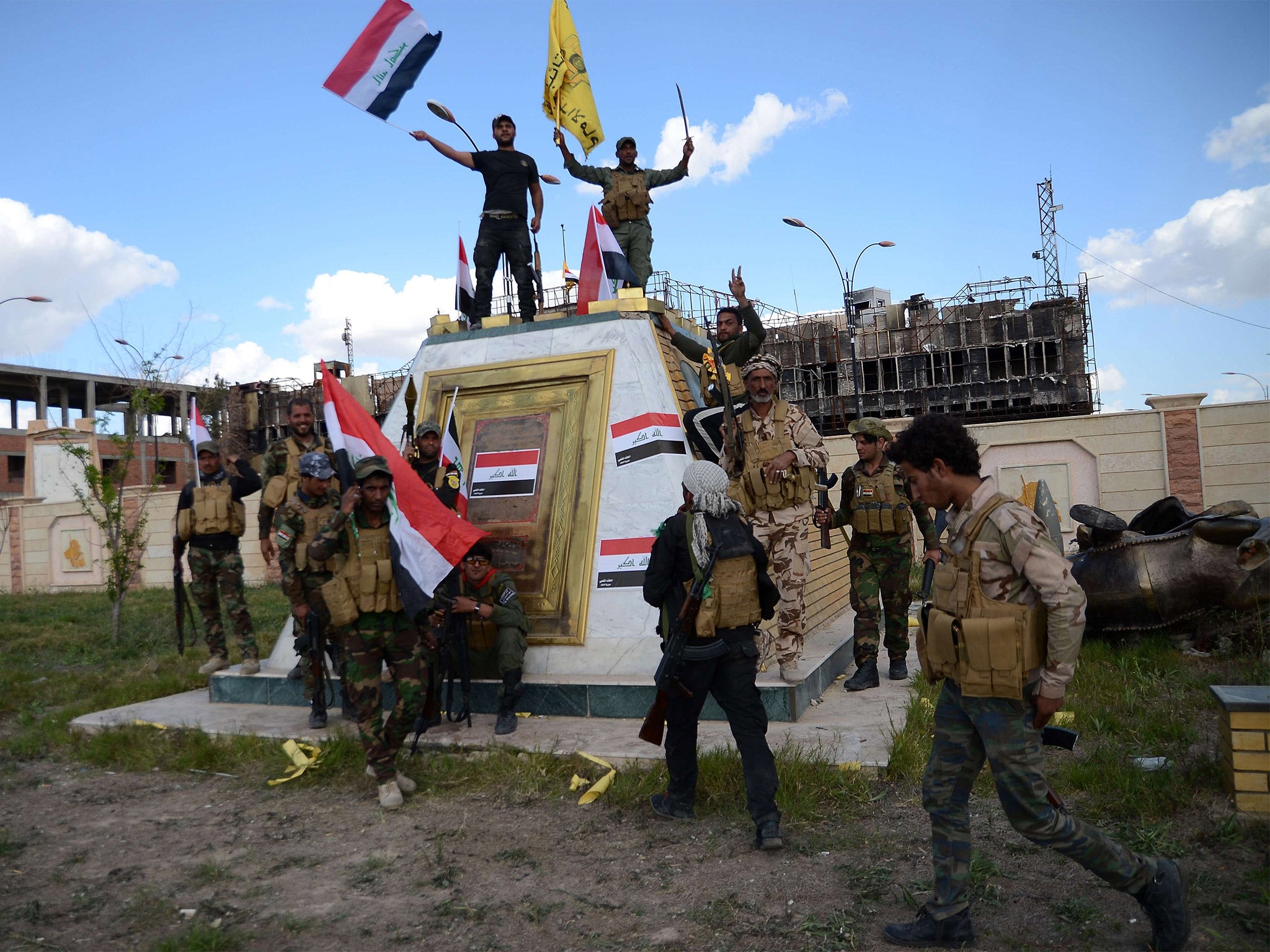 Shiite fighters celebrate in front of the the provincial council building inside the northern Iraqi city of Tikrit