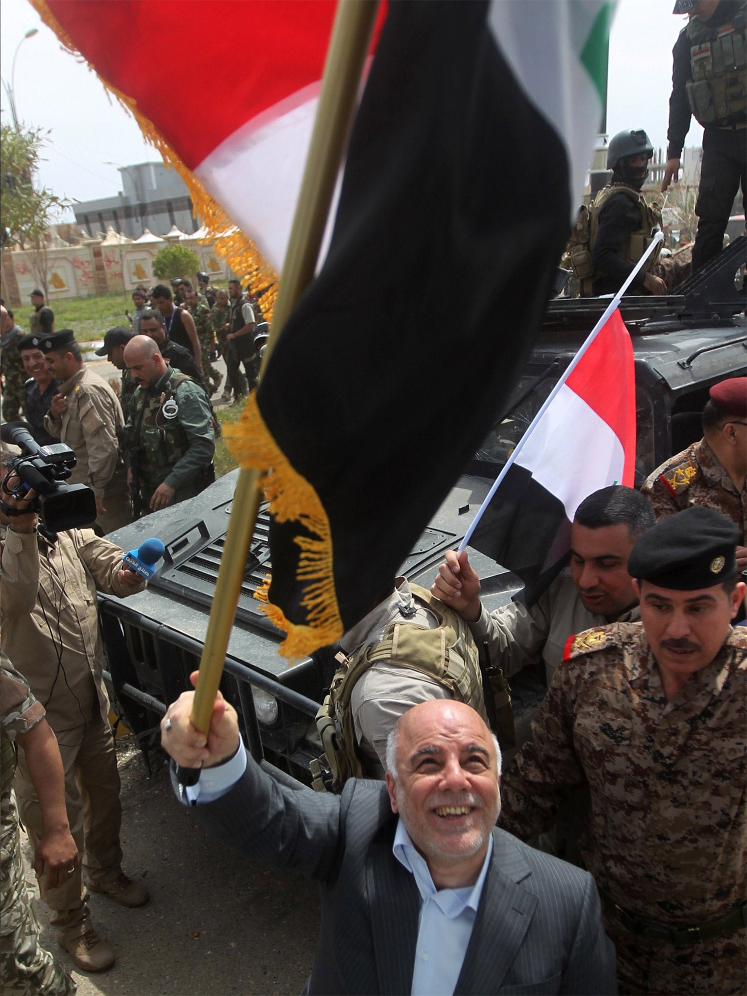 The Iraqi Prime Minister Haider al-Abadi waves his national flag while celebrating the retaking of the city of Tikrit (Getty)