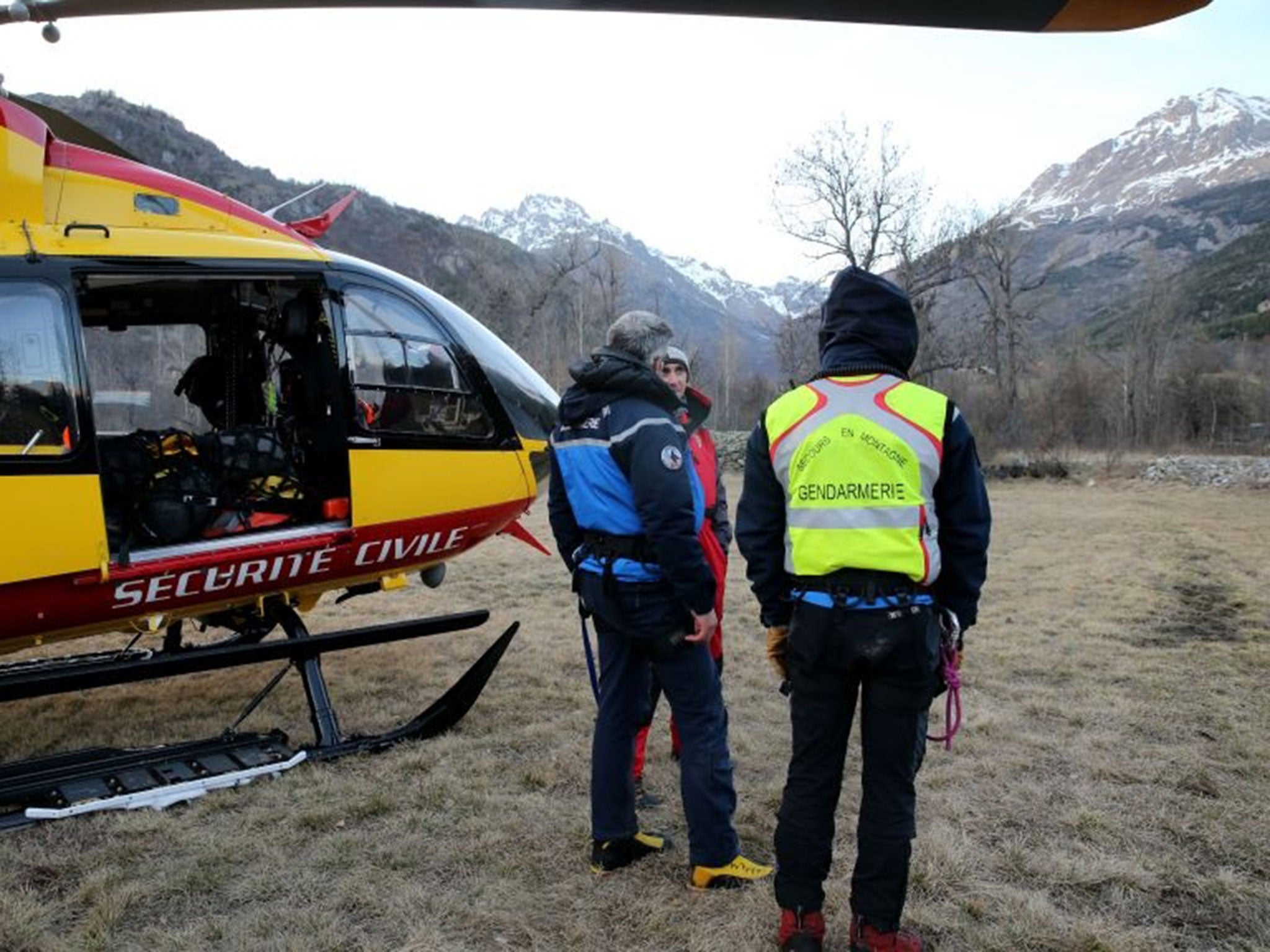 French gendarmes and rescuers stand near a helicopter on April 1, 2015 in Vallouise, in the French Alps, after searching for the victims of an avalanche which took place in the afternoon in the mountains of the Massif des Ecrins, killing three people.