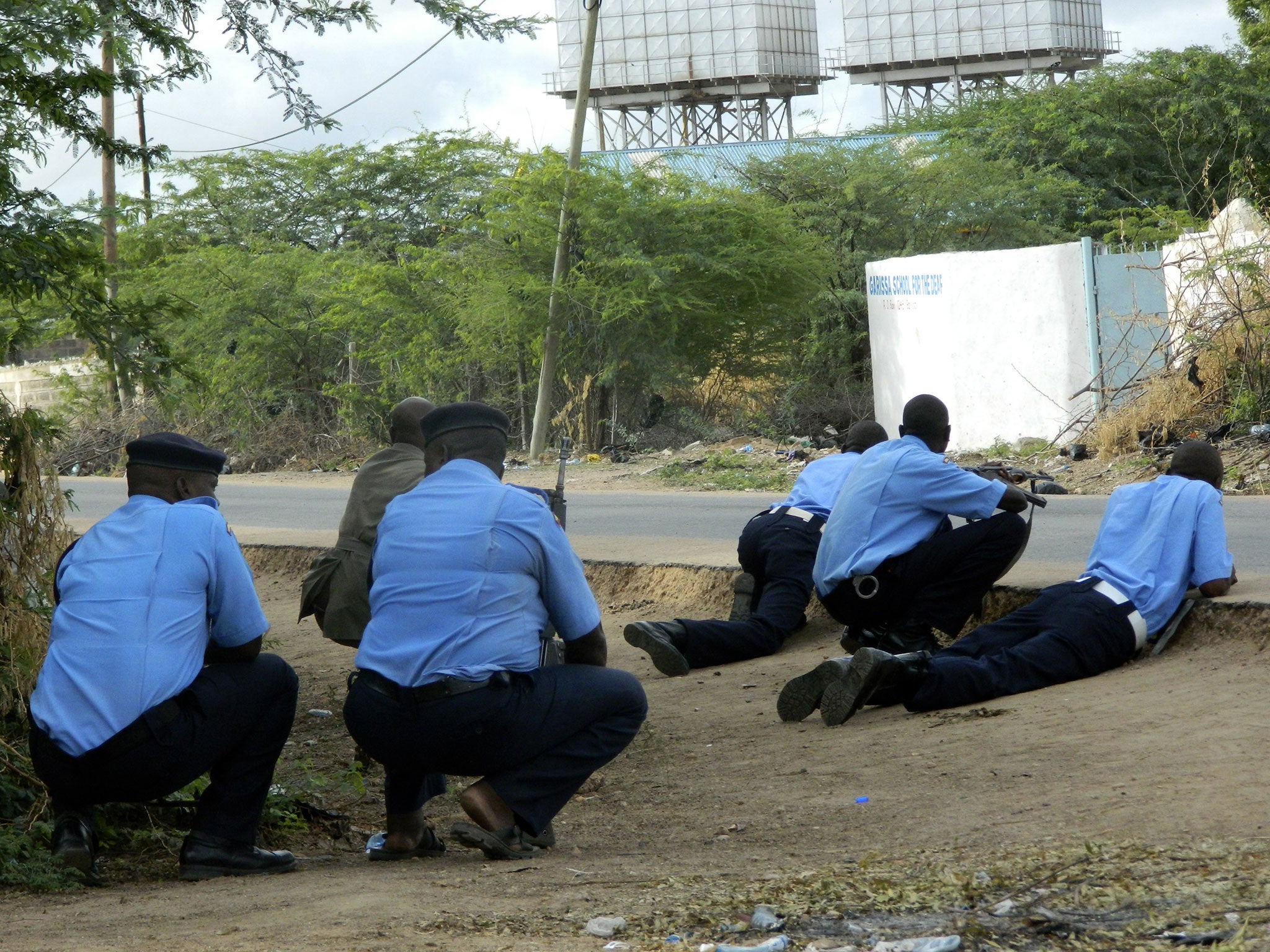 Kenyan police officers take cover outside the Garissa University College during an attack by gunmen in Garissa, Kenya