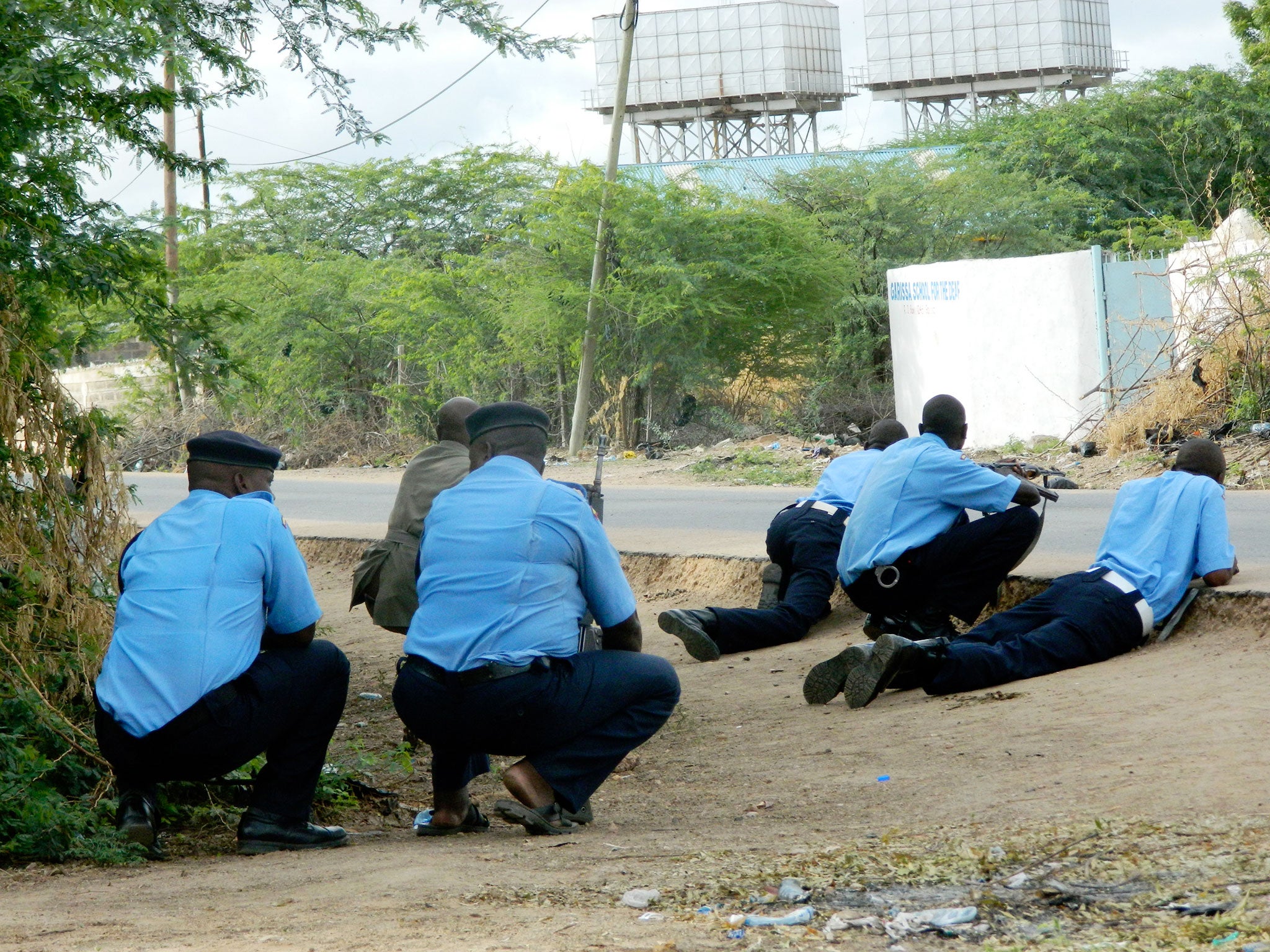 Kenyan police officers take cover outside the Garissa University College during an attack by gunmen in Garissa