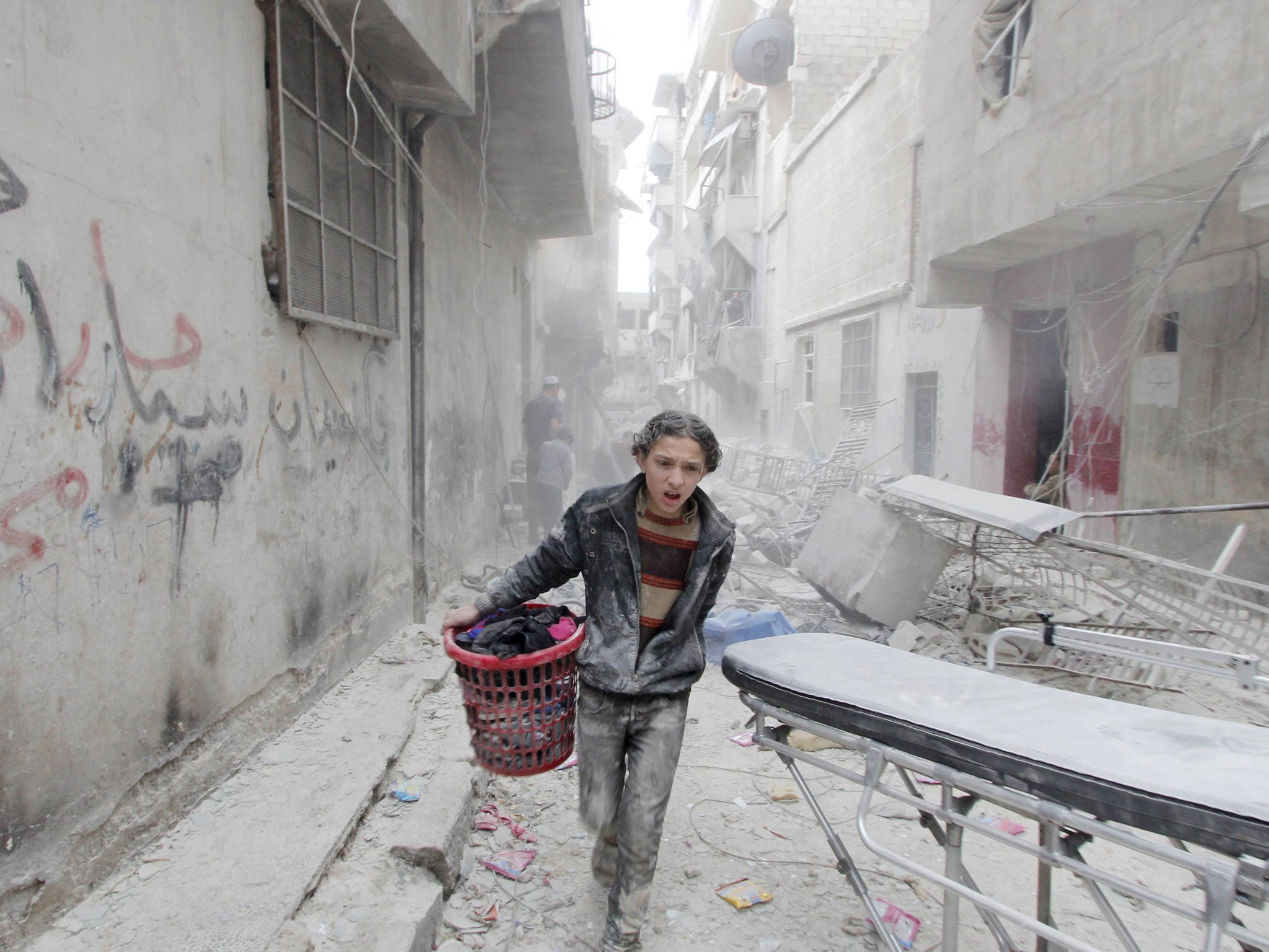 A boy carries his belongings at a site hit by what activists said was a barrel bomb dropped by forces loyal to Syria's President Bashar al-Assad in Aleppo's al-Fardous district