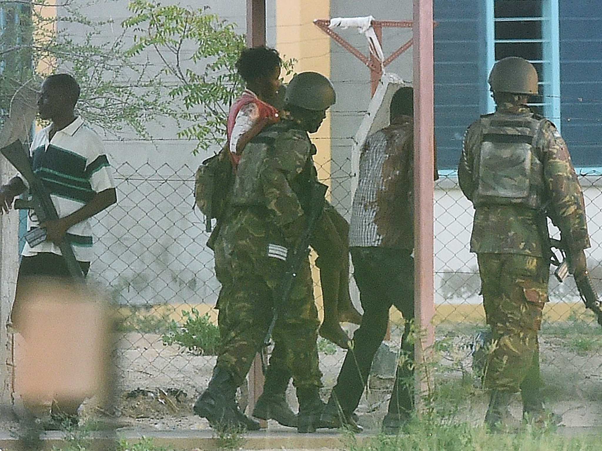 Two injured students being helped off the university campus by Kenyan soldiers