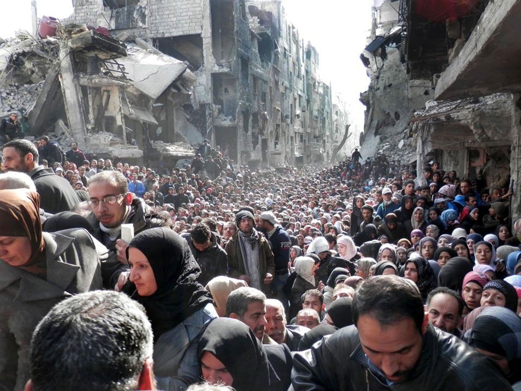 Palestinian refugees shown queuing for food supplies in the Yarmouk refugee camp last year