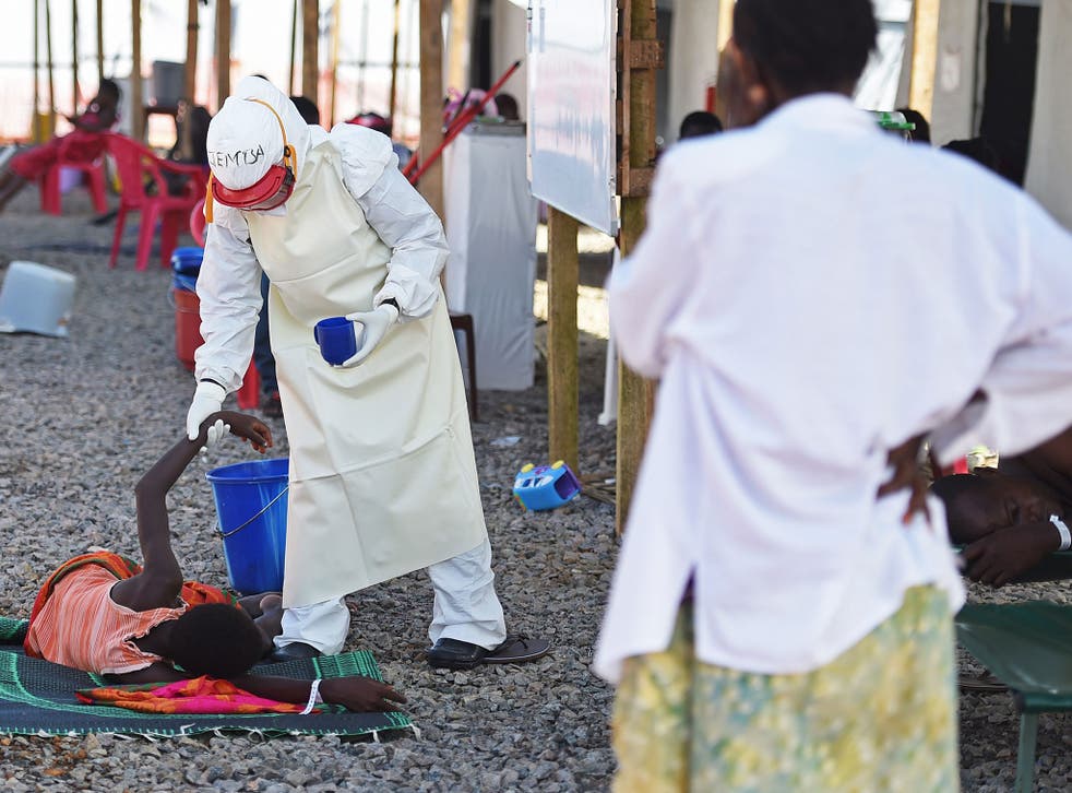 A health worker in protective clothing tends to an Ebola patient at a Sierra Leone Red Cross centre