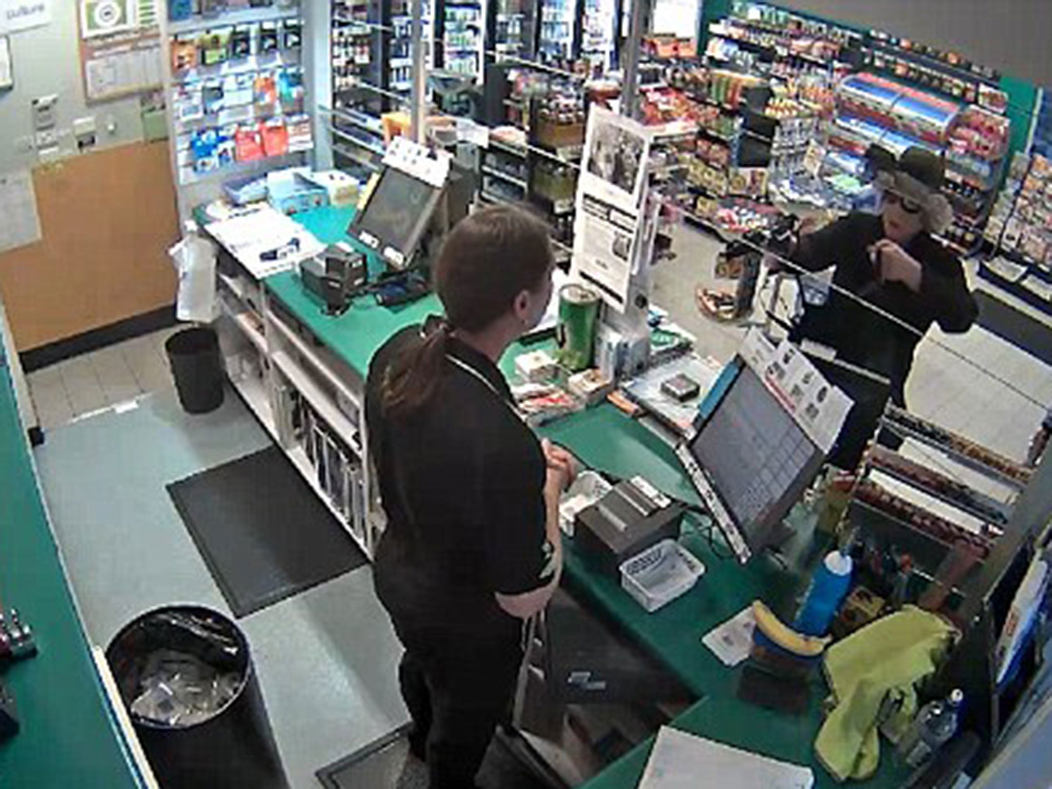 The cross-dressing robber was filmed looking around the shop before threatening the cashier with the weapon