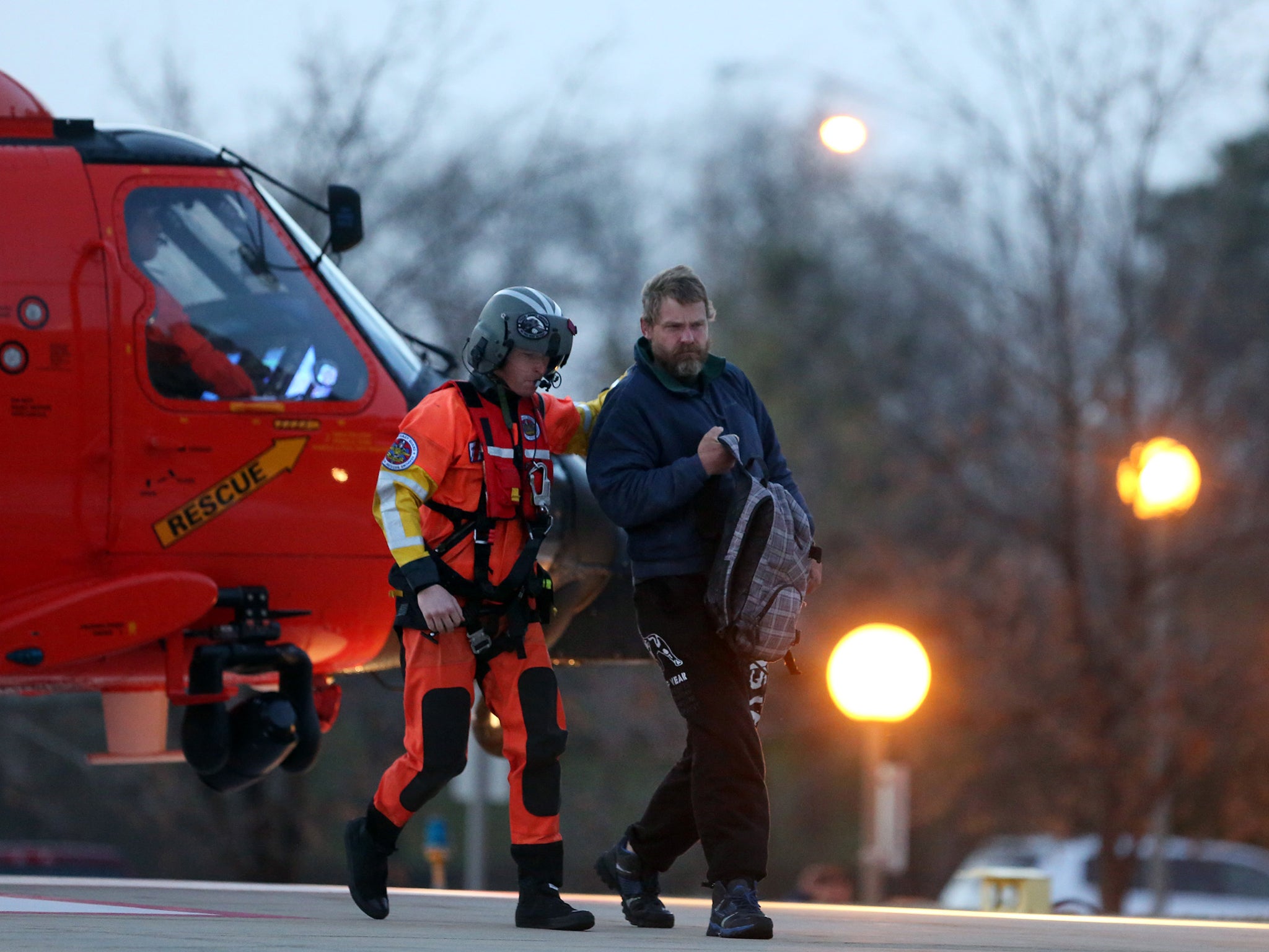 Louis Jordan, right, walks from the Coast Guard helicopter to the Sentara Norfolk General Hospital in Norfolk, Va., after being found off the North Carolina coast