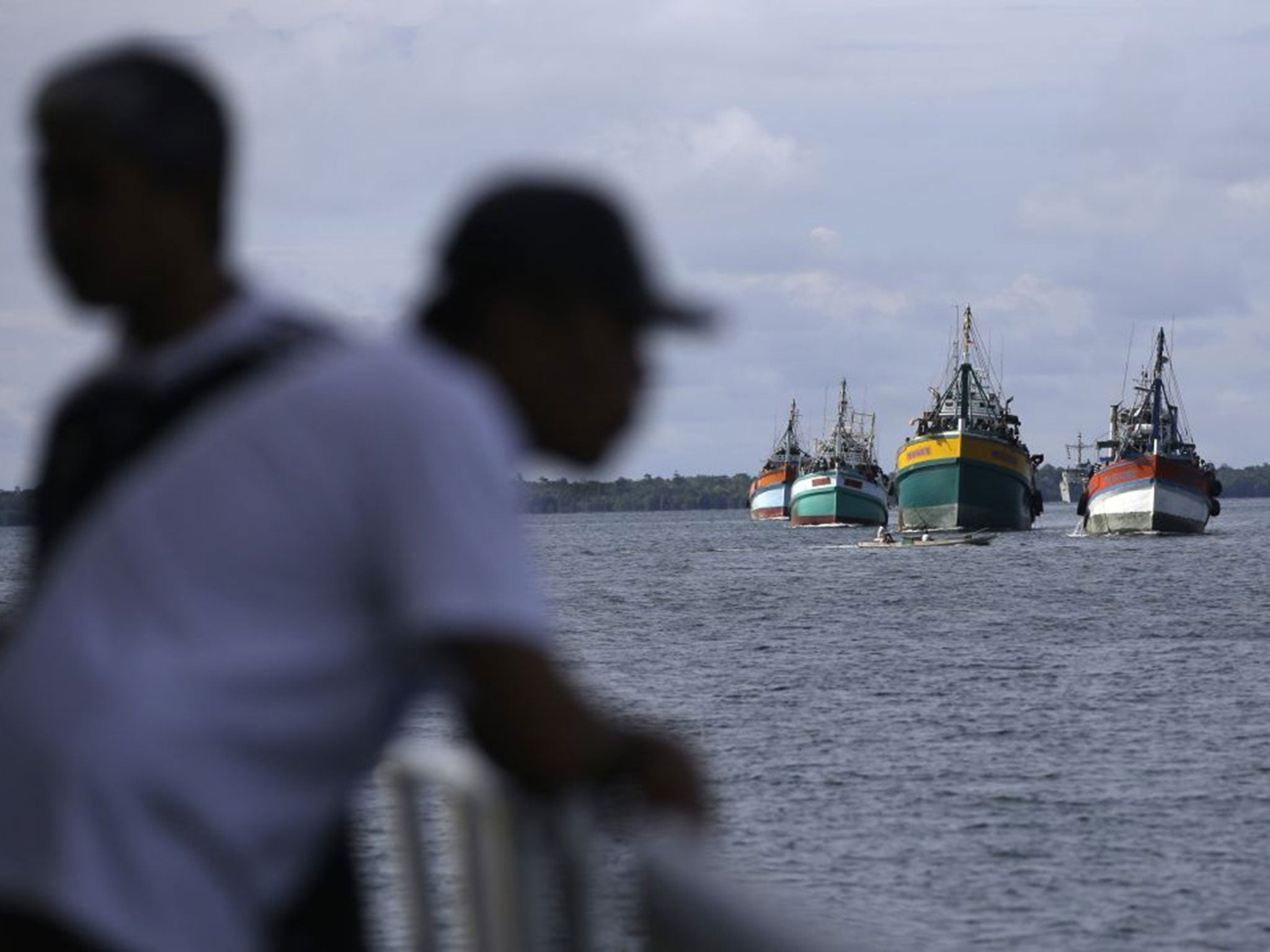 Fishing boats carrying recently rescued fishermen sail toward the town of Tual, Indonesia, Saturday, April 4, 2015. The rescued fishermen were among hundreds of migrant workers revealed in an Associated Press investigation to have been lured or tricked in