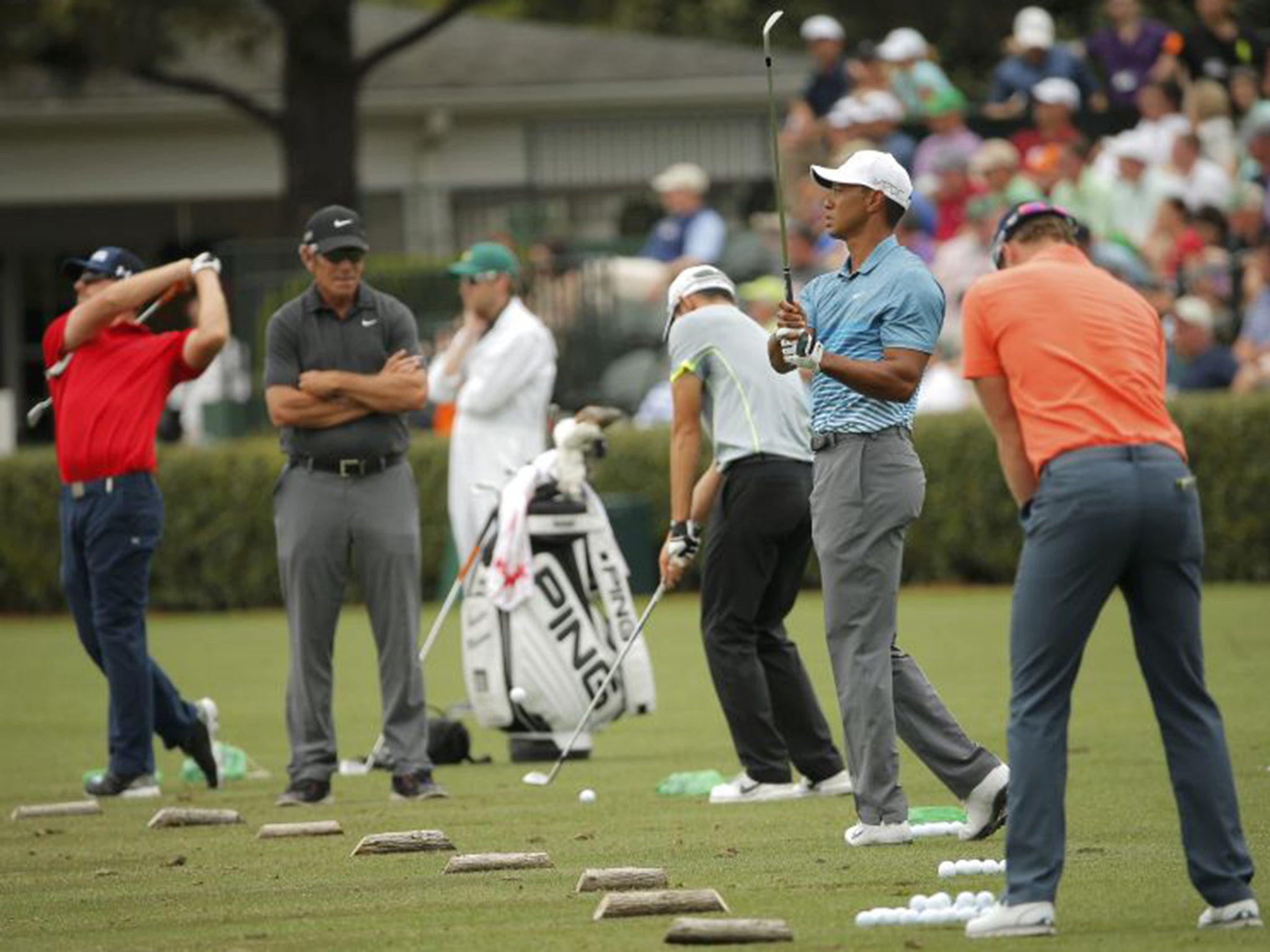 Tiger Woods, second right, warms up on the driving range during his practice round at Augusta National in Georgia on Monday