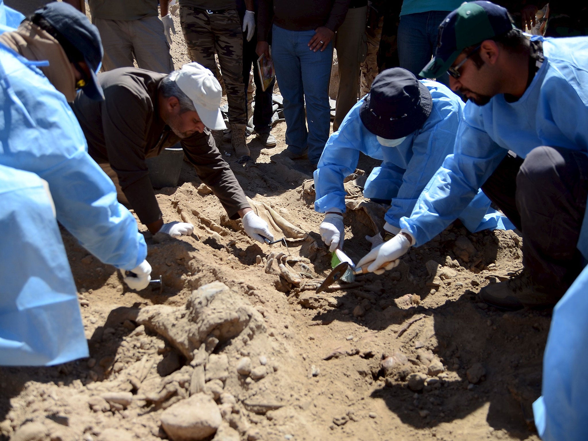 Members from the Iraqi forensic team search to extract the remains of the bodies