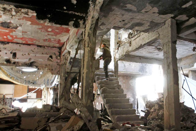 A man stands on a staircase inside a demolished building inside the Yarmuk Palestinian refugee camp