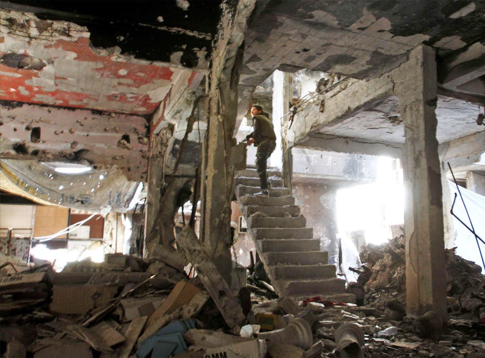 A man stands on a staircase inside a demolished building inside the Yarmuk Palestinian refugee camp