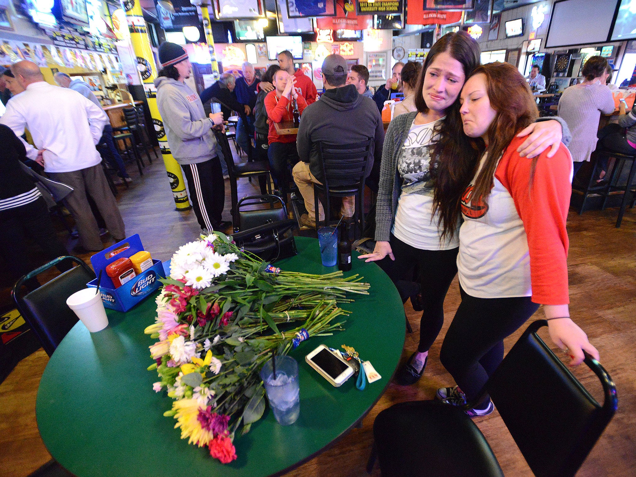 Waitresses cry prior at the downtown Normal bar in memory of co-owner Terry Stralow, one of victims on board